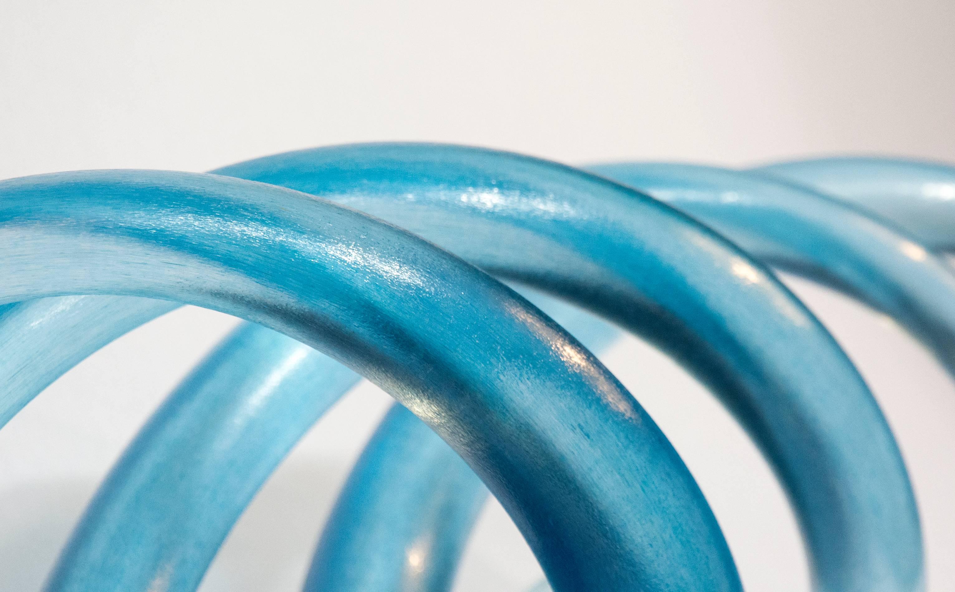 Metaphors of time, space, earth and its elements are reflected in the elegant and glowing glass sculptures by Canadian artist John Paul Robinson. In this table-top piece, gently curved tubes of azure blue glass move together mimicking the effect of