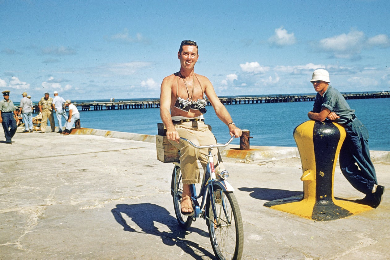 Slim Aarons riding a bike along the quayside in Hawaii with cameras slung around his neck during the filming of 'Mister Roberts' in 1954.

state stamped and hand numbered edition of 150 with certificate of authenticity from the estate. 

Slim Aarons