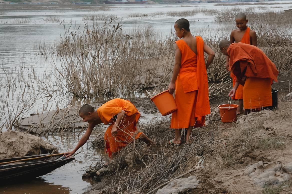 Deirdre Allinson Figurative Photograph - Novice Monks Collecting Mud in Luang Prabang, Laos.