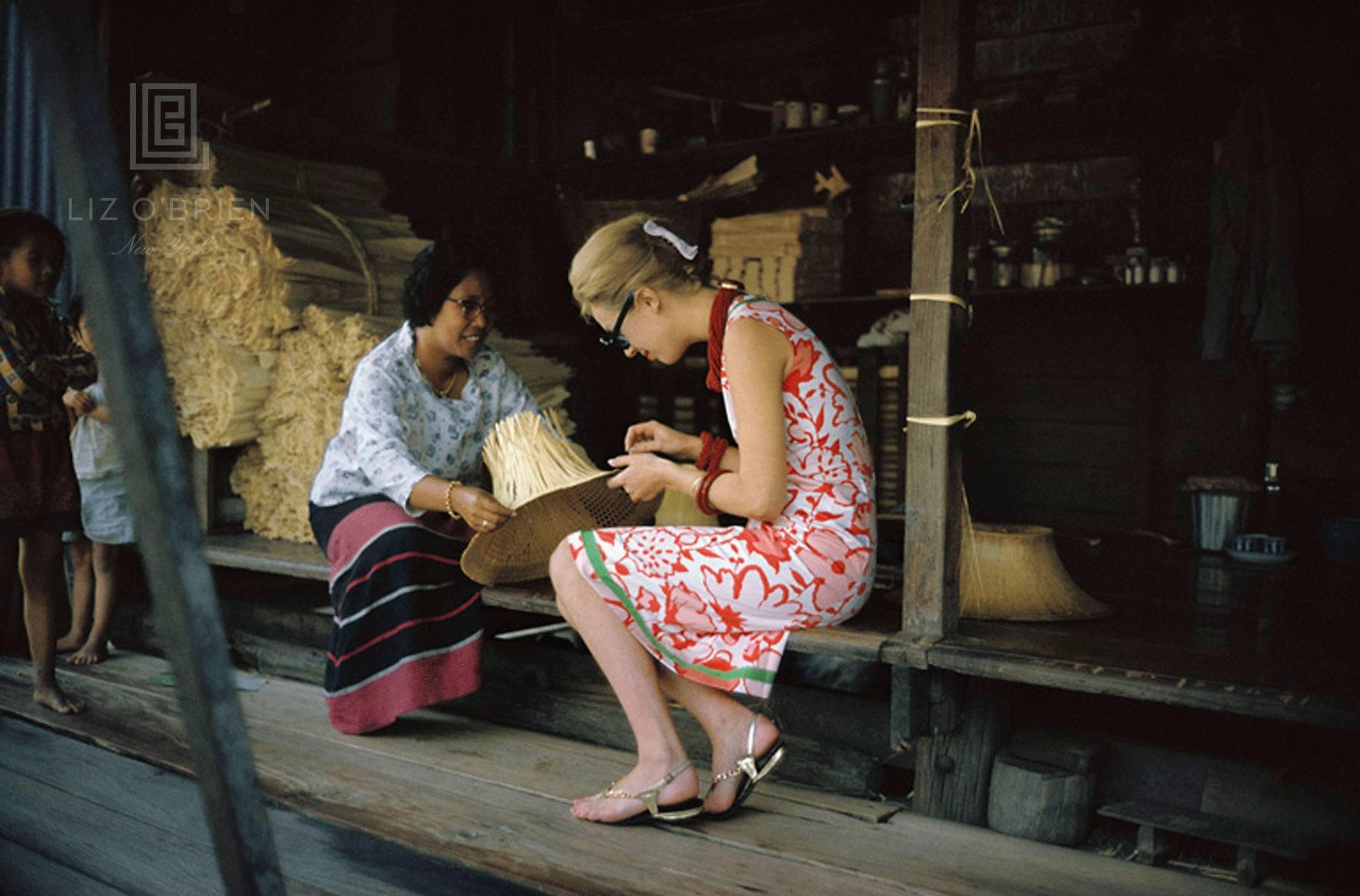 Mark Shaw Color Photograph - Tiger Morse Examines a Straw Hat, Bangkok, 1962