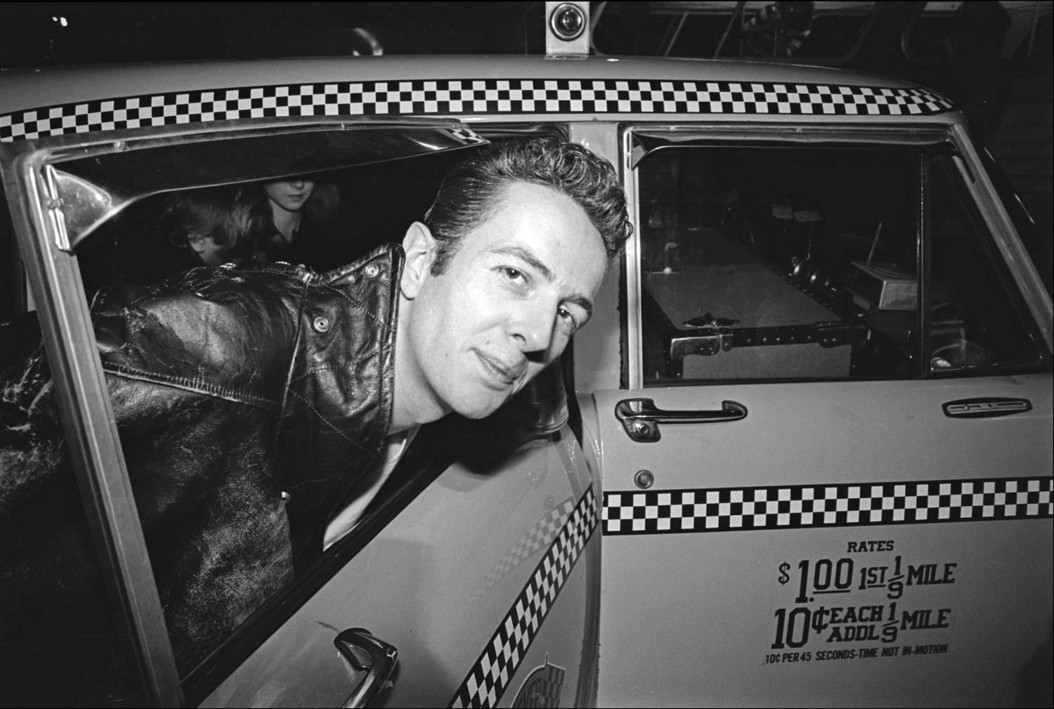 Black and White Photograph de Allan Tannenbaum - The Clash llegan al aeropuerto JFK - Joe Strummer sube a un taxi, 1981