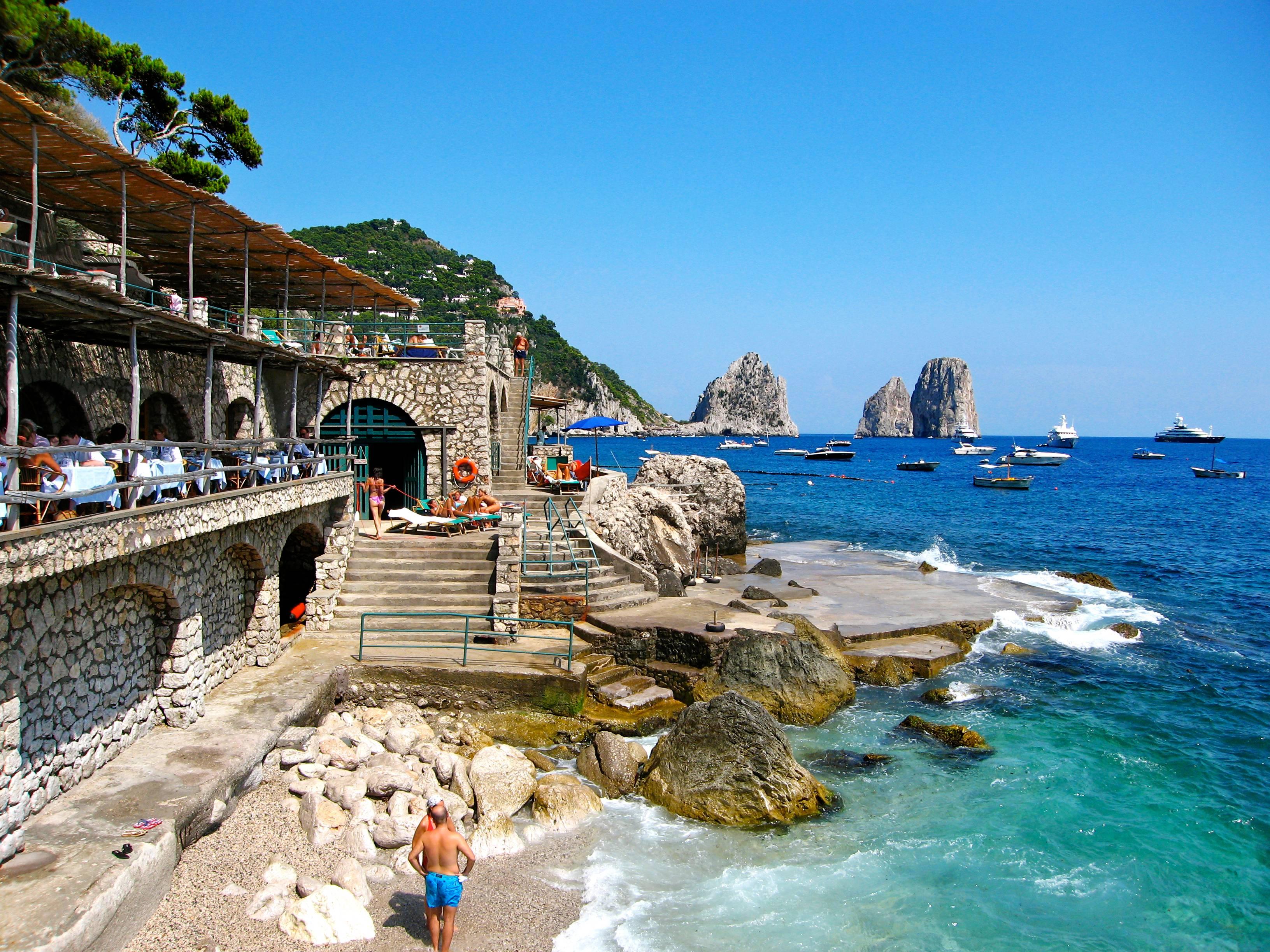 Capri Beach Club, Capri, Italie" par DJ Leon.   Photographie d'archive en tirage C de la célèbre scène du club de plage pendant les mois d'été, montée sur sintra, et face montée en plexiglas. La photographie est  mesure 30 x 44 pouces, Ed. de 9.