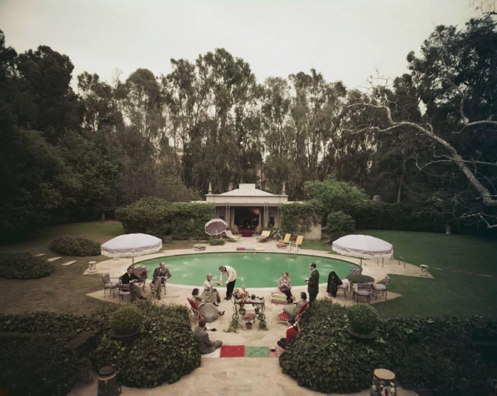 'Scone Madam' by Slim Aarons

Afternoon tea round the pool on a cold day at the home of interior decorator James Pendleton in Beverly Hill, 1960. 

Fashionably smartly dressed guests enjoy afternoon tea  served by a butler beside the swimming pool