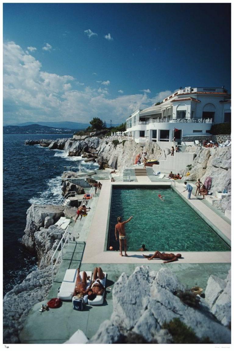 'Eden-Roc Pool' (Slim Aarons Estate Edition)

A fabulous Slim! 
Another version of the now Slim 'classic' and hugely popular 'Hotel Du Cap Eden-Roc.' (Also available from us)

Guests round the swimming pool at the Hotel du Cap Eden-Roc, Antibes,