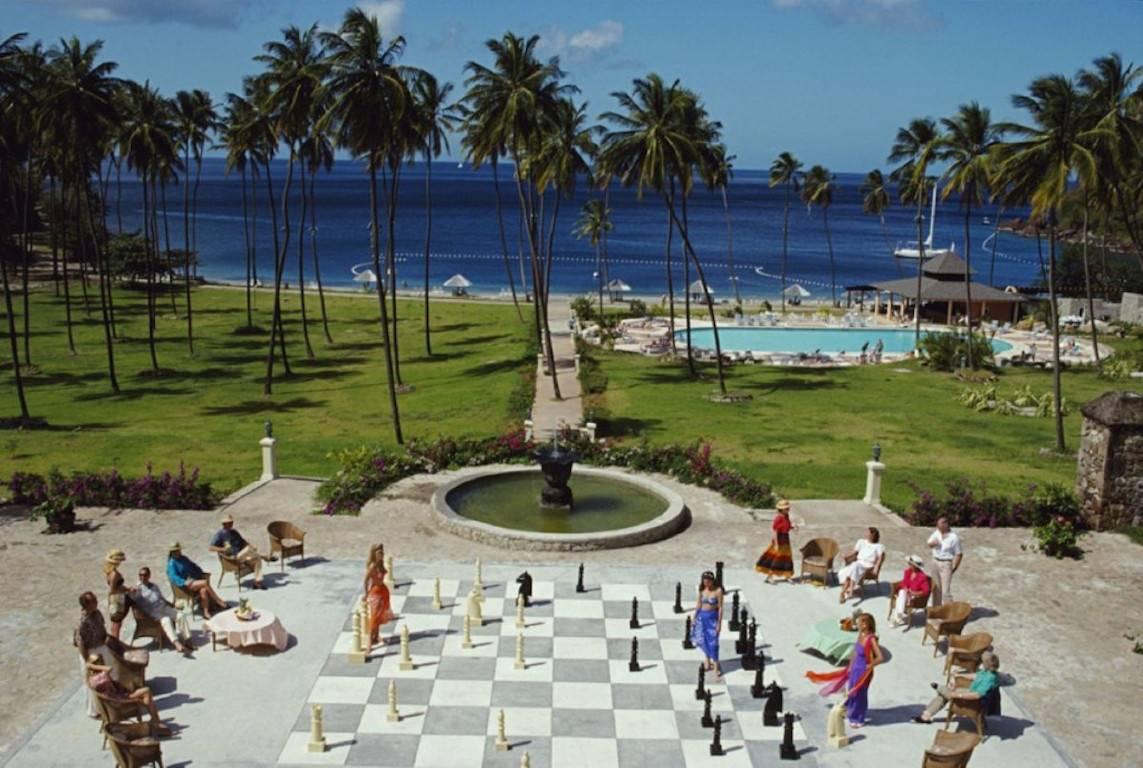 megachess  (Slim Aarons Estate Edition)

Eine riesige Schachpartie auf St. Lucia, auf den Kleinen Antillen, Februar 1993.

Eine einfach fabelhafte Szene!
Zwei junge Frauen in farbenfrohen Kleidern sind zu sehen, die abwechselnd auf dem riesigen