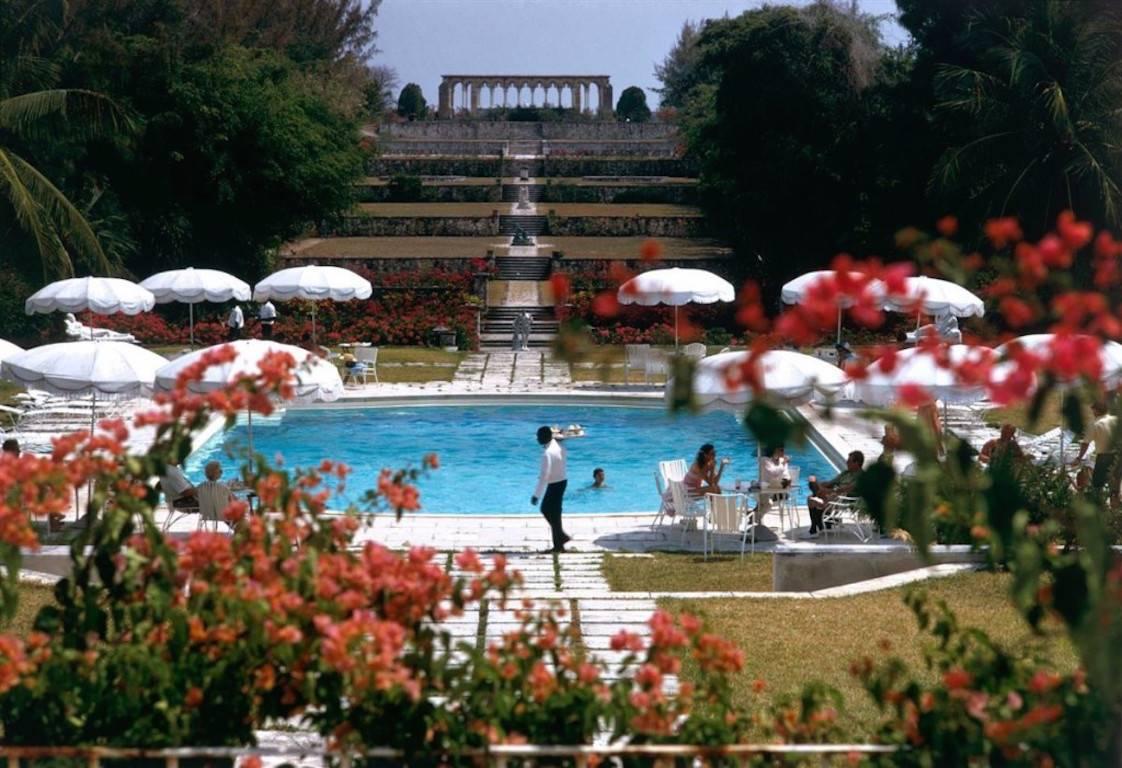 'Ocean Club' by Slim Aarons

Versailles Gardens at the Ocean Club, Nassau with terraced steps leading from a swimming pool to a 14th century French cloisters, 1968.

A sumptuous and gorgeous scene bursting with colour. 
A waiter dressed elegantly in