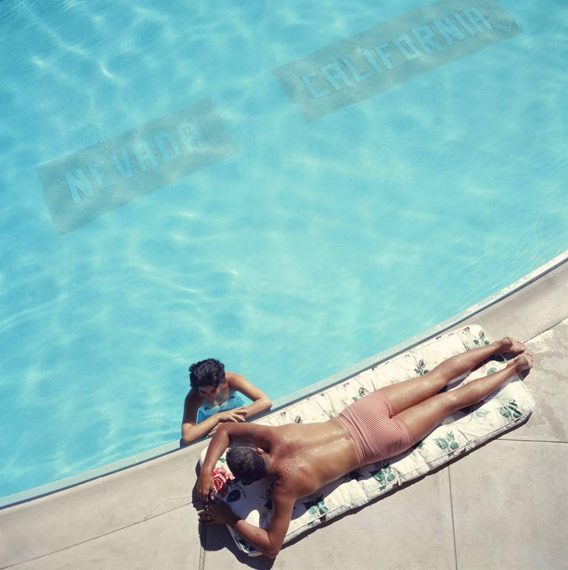 'Lake Tahoe Couple' Slim Aarons Estate Edition

Ein Paar entspannt sich an einem Swimmingpool in der Sommersonne in der Nähe des Lake Tahoe, Kalifornien, 1959. Die Linie auf dem Boden des Pools markiert die Staatsgrenze zwischen Nevada und