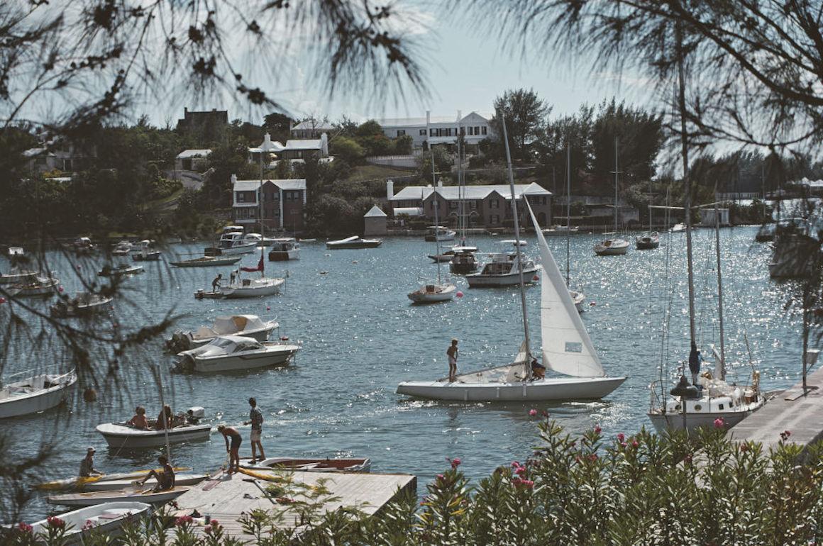  Der Royal Hamilton Amateur Dinghy Club" von Slim Aarons
Mitglieder des Royal Hamilton Amateur Dinghy Club bereiten sich auf das Segeln in Bermuda vor, 1976

Dieses Foto verkörpert den Reisestil und den Glamour der Reichen und Berühmten dieser Zeit,