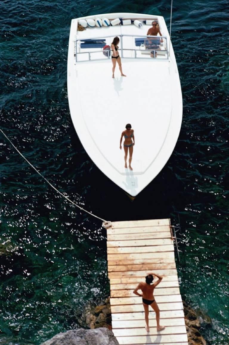 schnellboot-Landung  (Slim Aarons Estate Edition)

Ein Magnum-Motorboot, das dem Grafen Filippo Theodoli gehört, kommt am Privatsteg des Hotels Il Pellicano in Porto Ercole, Italien, 1973, an.

Ein modernes klassisches "Sim Aarons"-Foto des