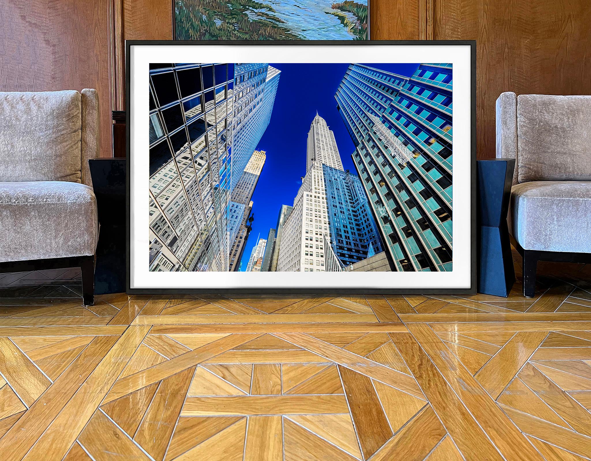 La scelta di una giornata perfetta, con una luce nitida e un cielo blu cobalto intenso, offre al fotografo Mitchell Funk l'ambiente ideale per creare una fotografia di East 42nd Street con il Chrysler Building, dal design preciso.  La composizione
