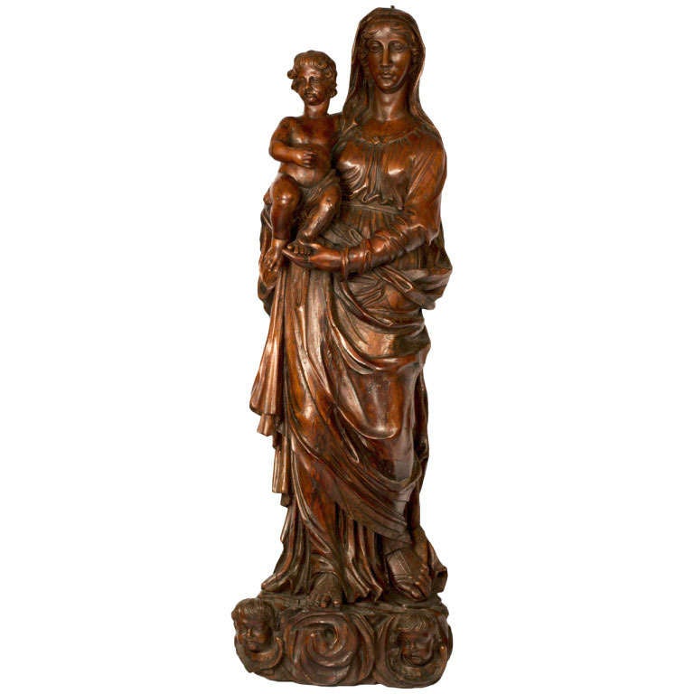 Mary stands on a plinth of cherubim, the moon, and linen folds, while holding the Christ child.