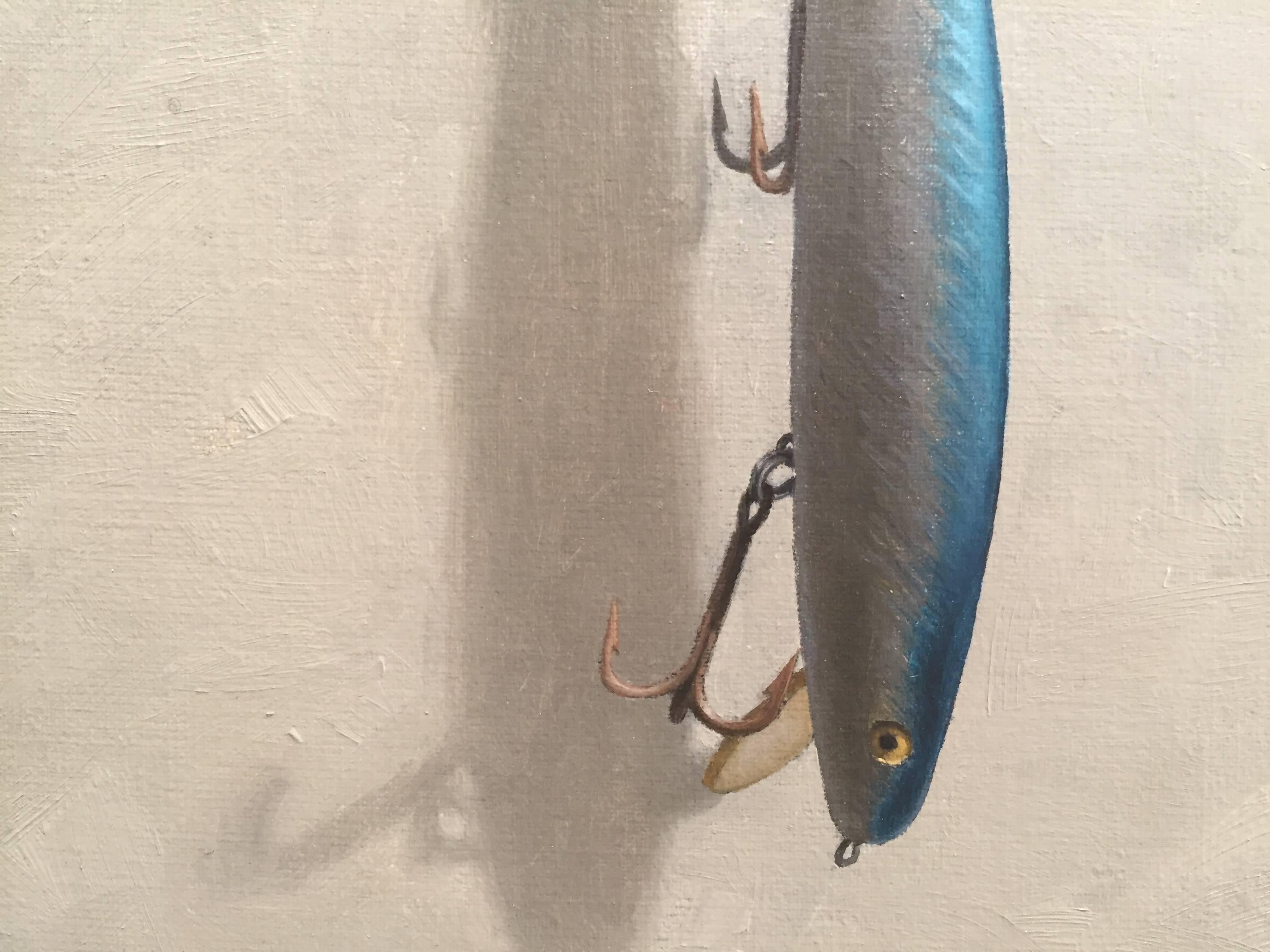 Painted from life in his Connecticut studio, Morfis paints a shimmering life-like fishing lure. Hanging from a tiny metal nail via an anchor shaped hook, the fish-like lure dangles upside down. The eye of the fish glares at the viewer impatiently. A