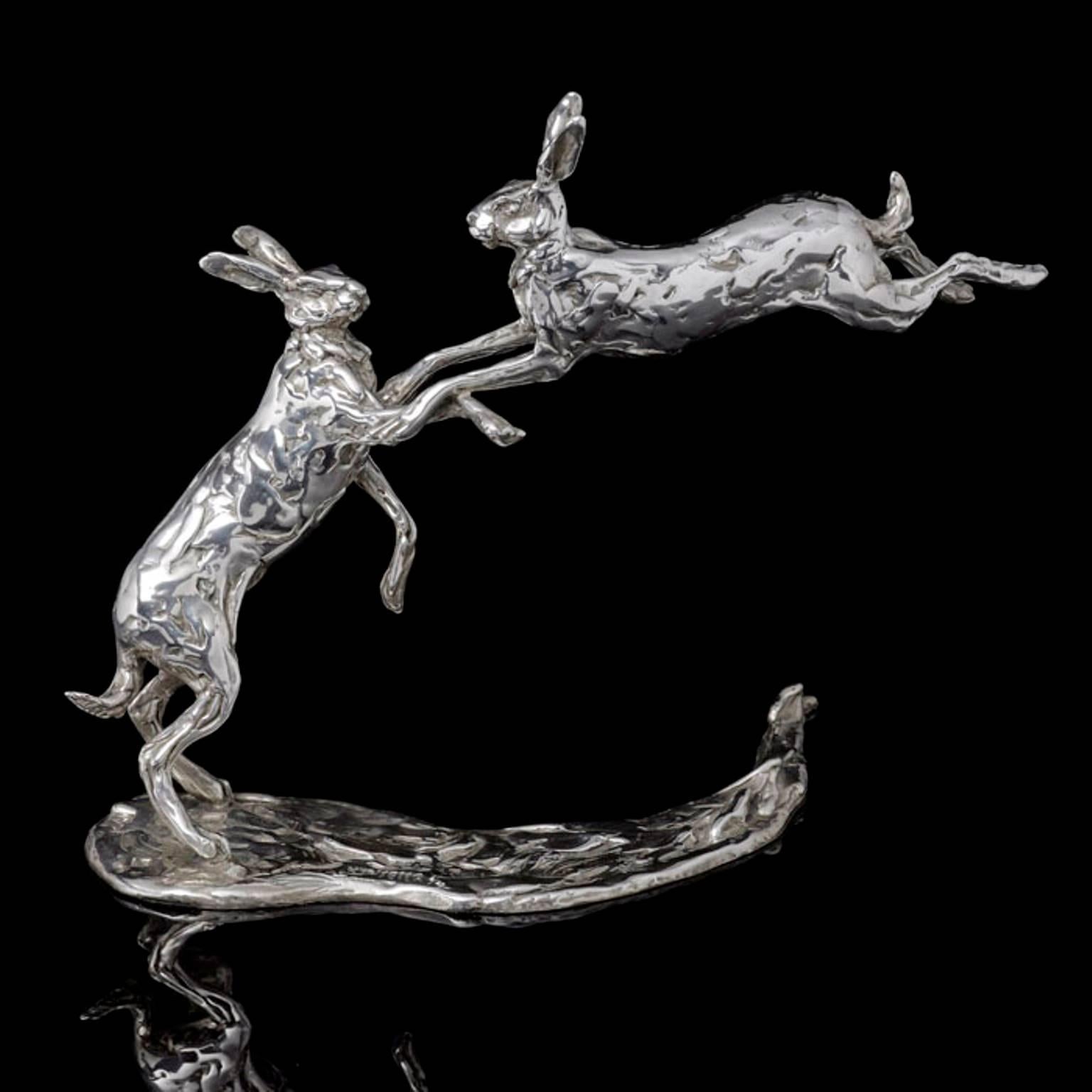 A ‘Leaping Hares’ sterling silver sculpture by Lucy Kinsella, the limited edition finely modelled pair of long eared hares caught mid confrontation with one stood tall on stretched hind legs, the other leaping through the air, front legs