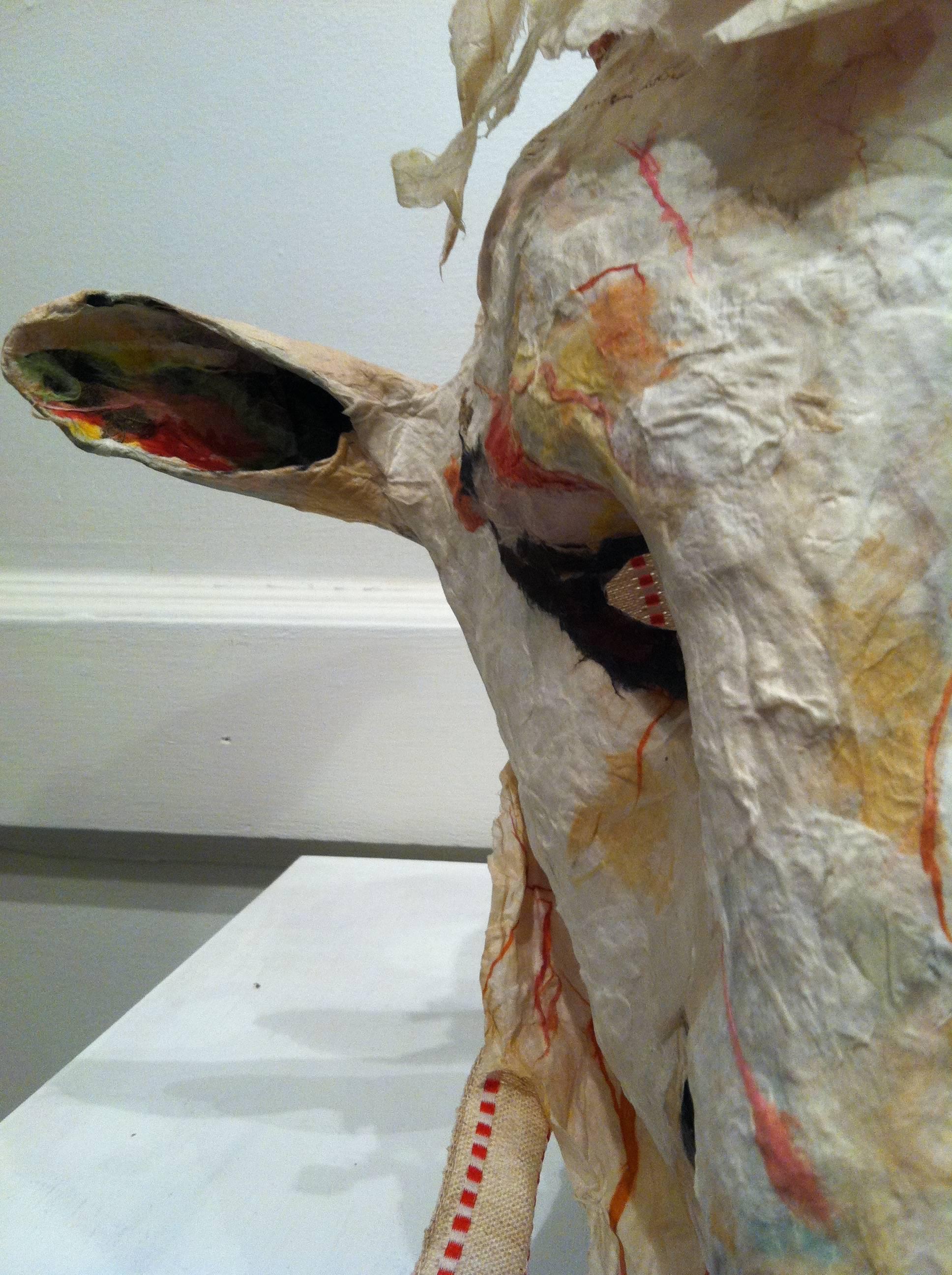 This sculptural mask is constructed in rice paper and mixed media materials. The mask has a dominant presence wherever it hangs. The anthropomorphic figure sometimes looks more animal, other times more human. It is lightly colored, akin to pearl