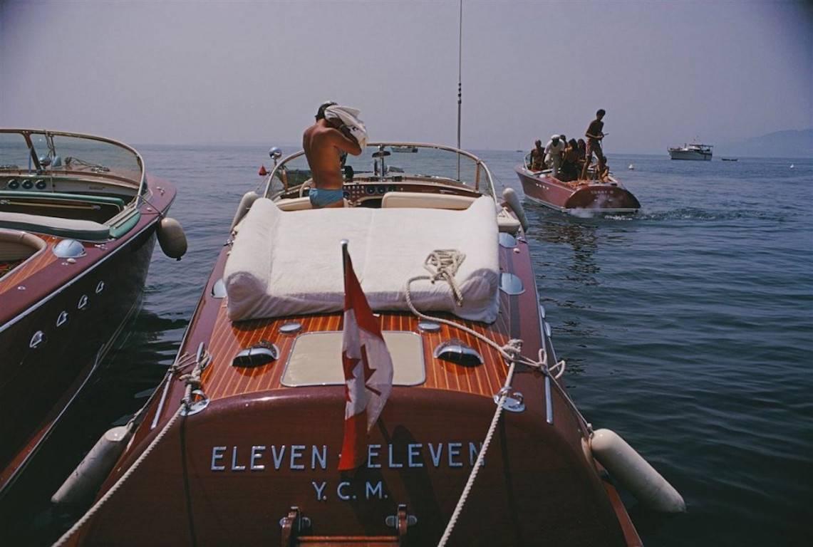 motorboote in Antibes" von Slim Aarons

Motorboote an der Küste in der Nähe des Hotel du Cap-Eden-Roc in Antibes an der Côte d'Azur, August 1969.

Vor dem kultigen Hotel an der glamourösen Côte d'Azur liegen wunderschöne Riva-Motorboote vor