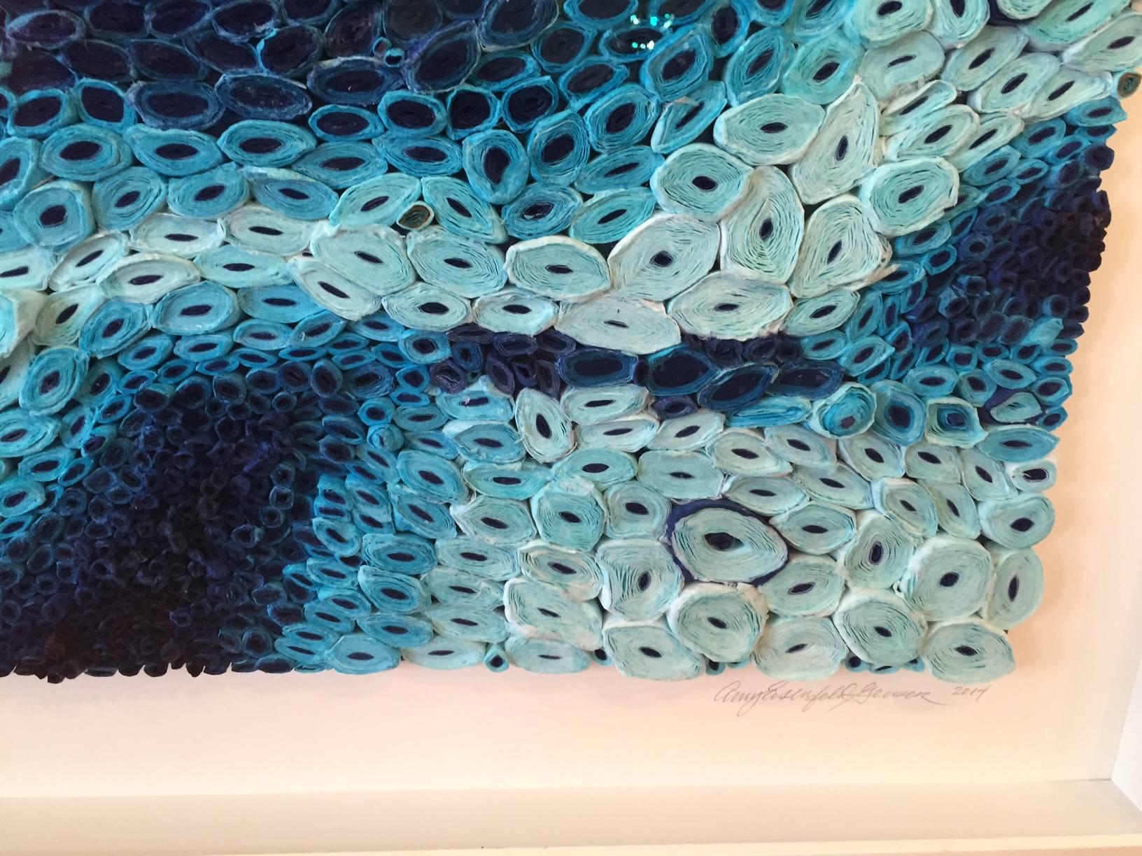 This blue mixed media piece is by Amy Genser who creates dimensional paper collages. These colorful, textural, one-of-a-kind wall pieces embody movement and processes. She masterfully manipulates paper -- each piece being cut, rolled and stacked --
