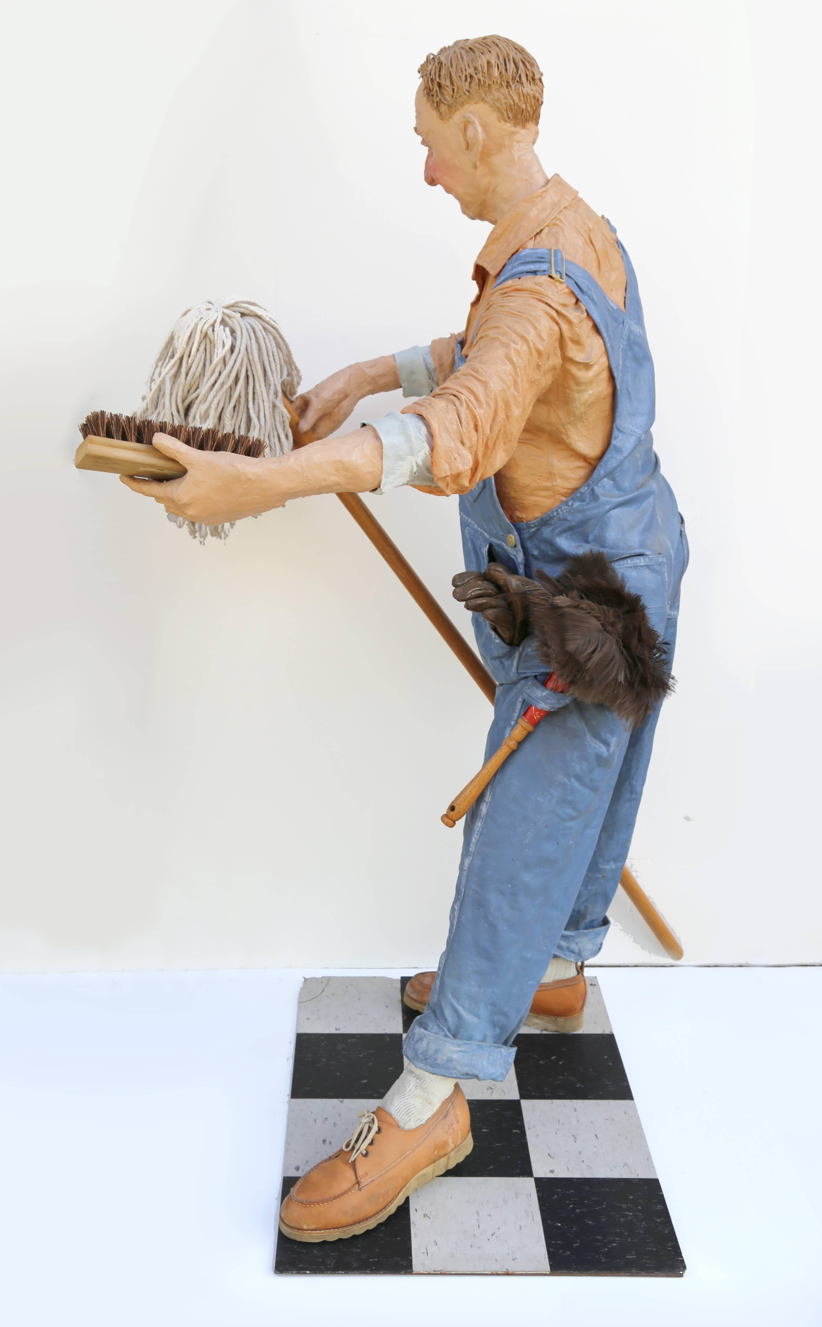Artist: Kay Ritter
Title: Janitor
Medium: Painted Papier-mache on Metal Base, with mop, duster, scrubbing brush, and key chain
Year: c. 1983
Size: 52  x 28  x 30 in. (132.08  x 71.12  x 76.2 cm)