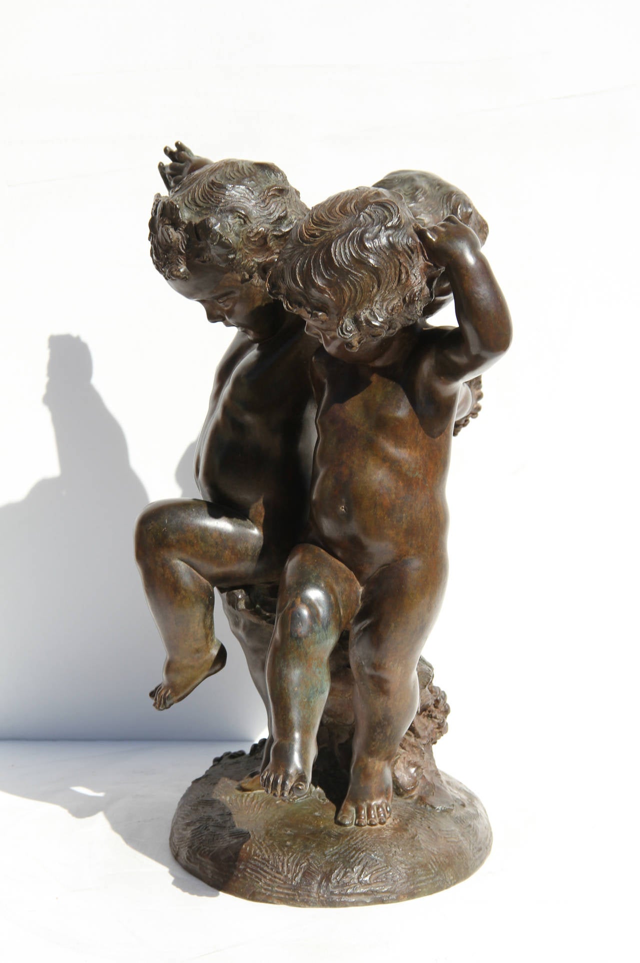 Esta escultura de bronce, obra del artista francés Affortunato Gory, es un bello momento de tres putti bailando alegremente juntos.  Sus brazos están unidos mientras bailan y toman uvas.  Firma inscrita.