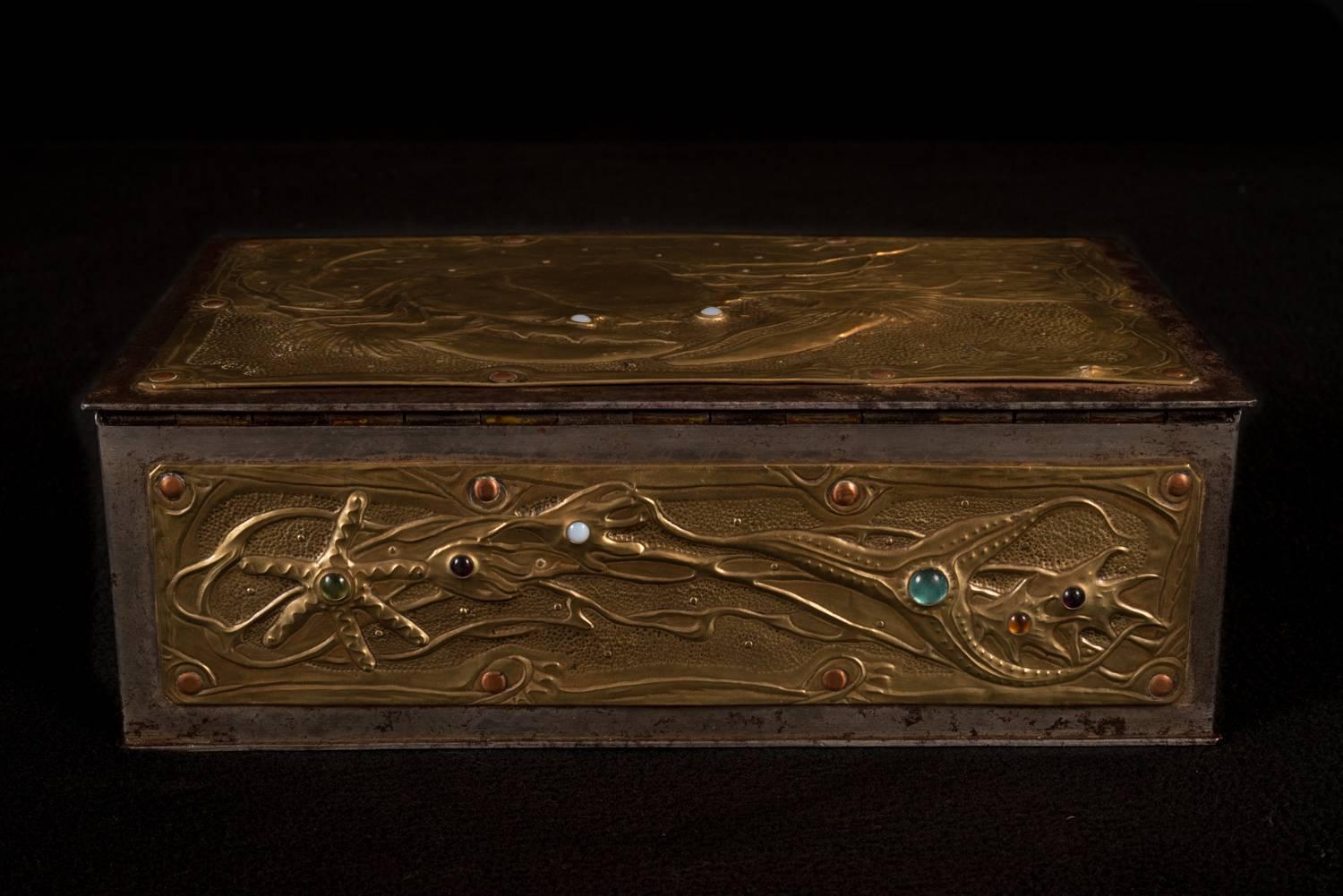 MYSTERIES OF THE OCEAN, Strongbox by Alfred Louis Achille Daguet, 1907, the iron box clad in brass sheets worked in repousse, finely chased and adorned with colored glass cabochons and secured by copper and brass nails, marked verso “4” painted in