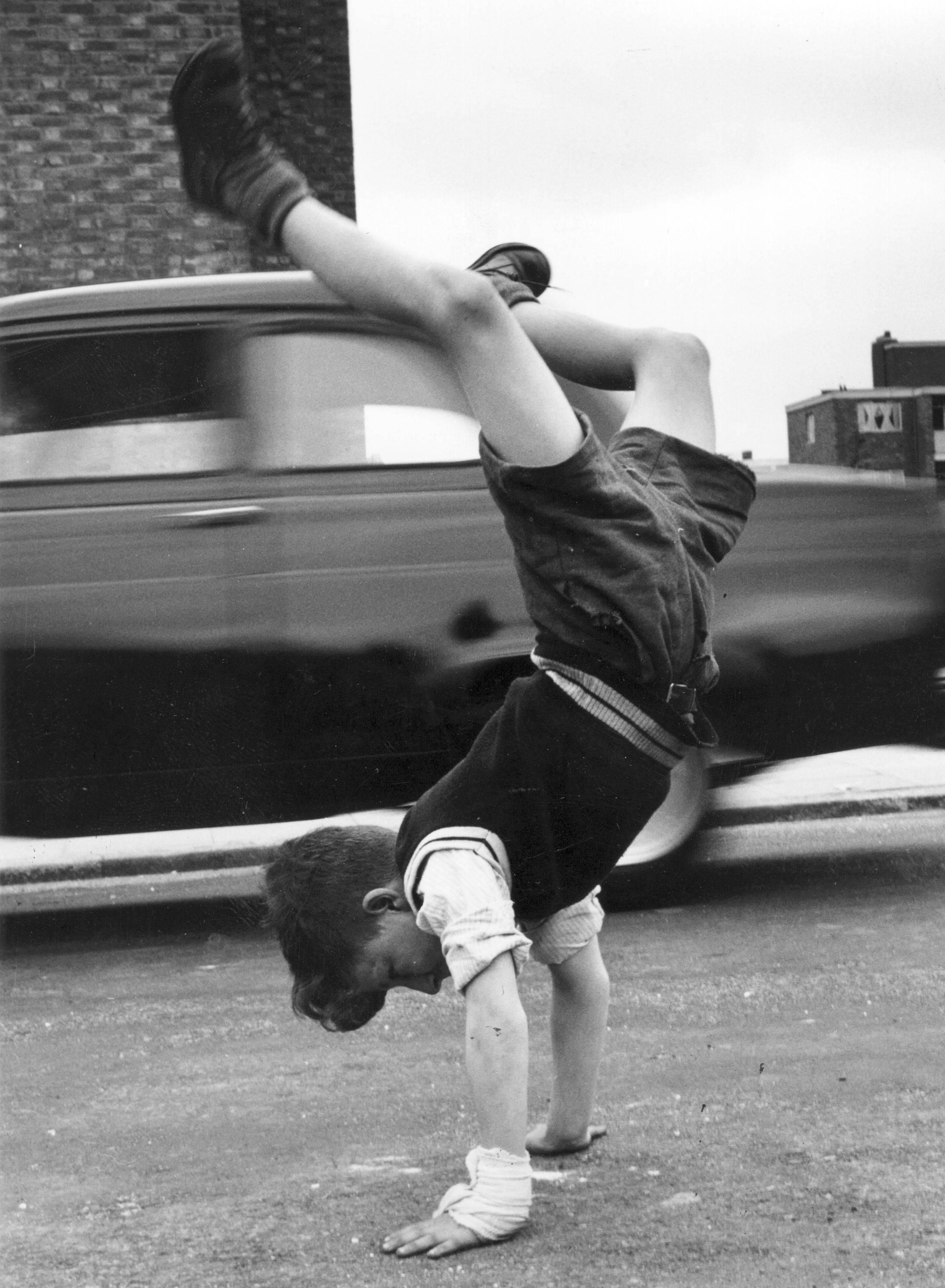 From the Picture Post collection, photographer Thurston Hopkins captures a young boy doing a handstand in the road.  The photograph was taken in London in 1954 as part of Hopkins' Children of the Streets project.  

- Rare signed print, signature on