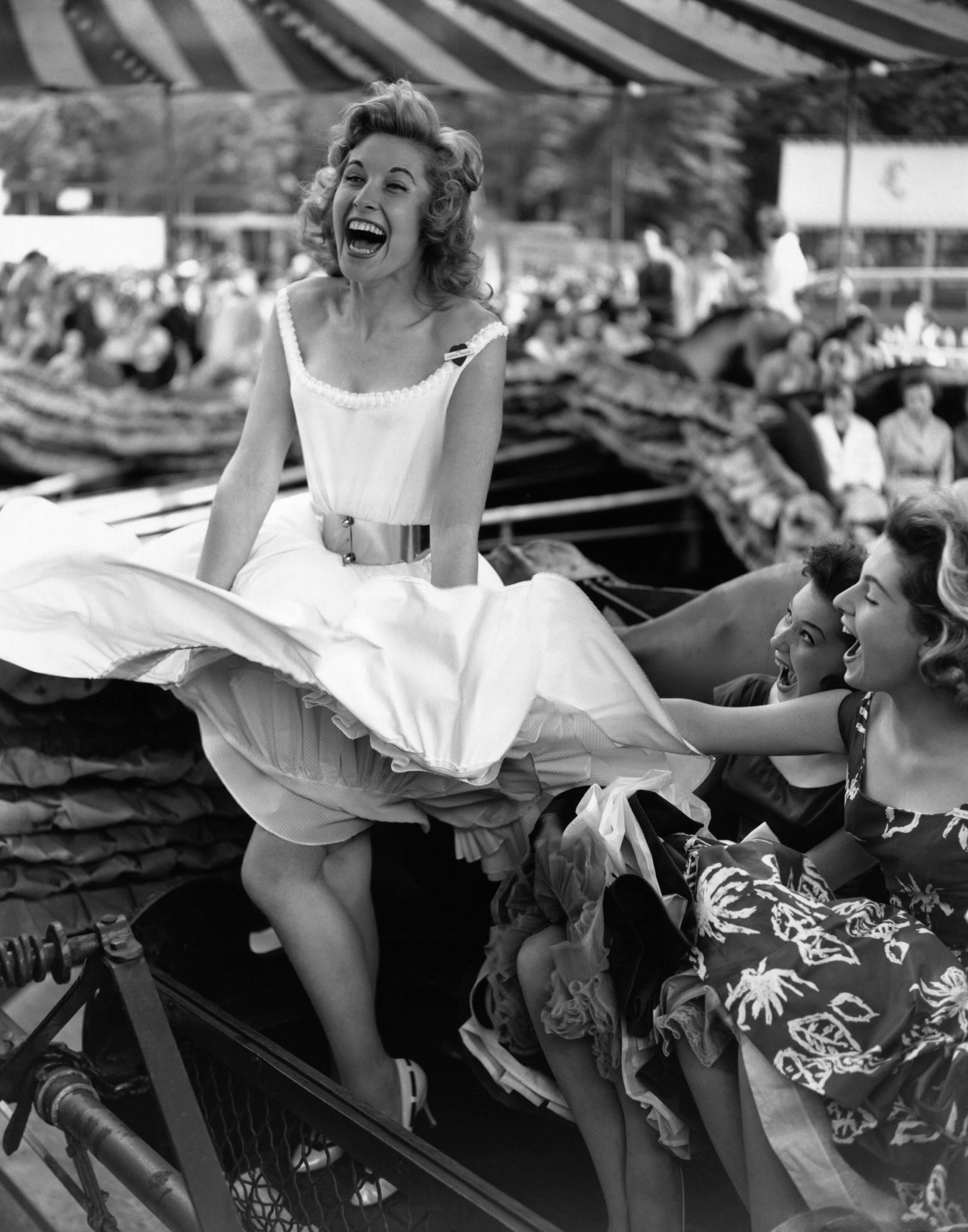 Three women enjoying the wind machine at the opening of the Festival Gardens fun fair, Battersea Park, London.

- Rare signed print, signature on front.
- Hand printed silver gelatin fibre photograph. 
- Printed using the original negative. 
-
