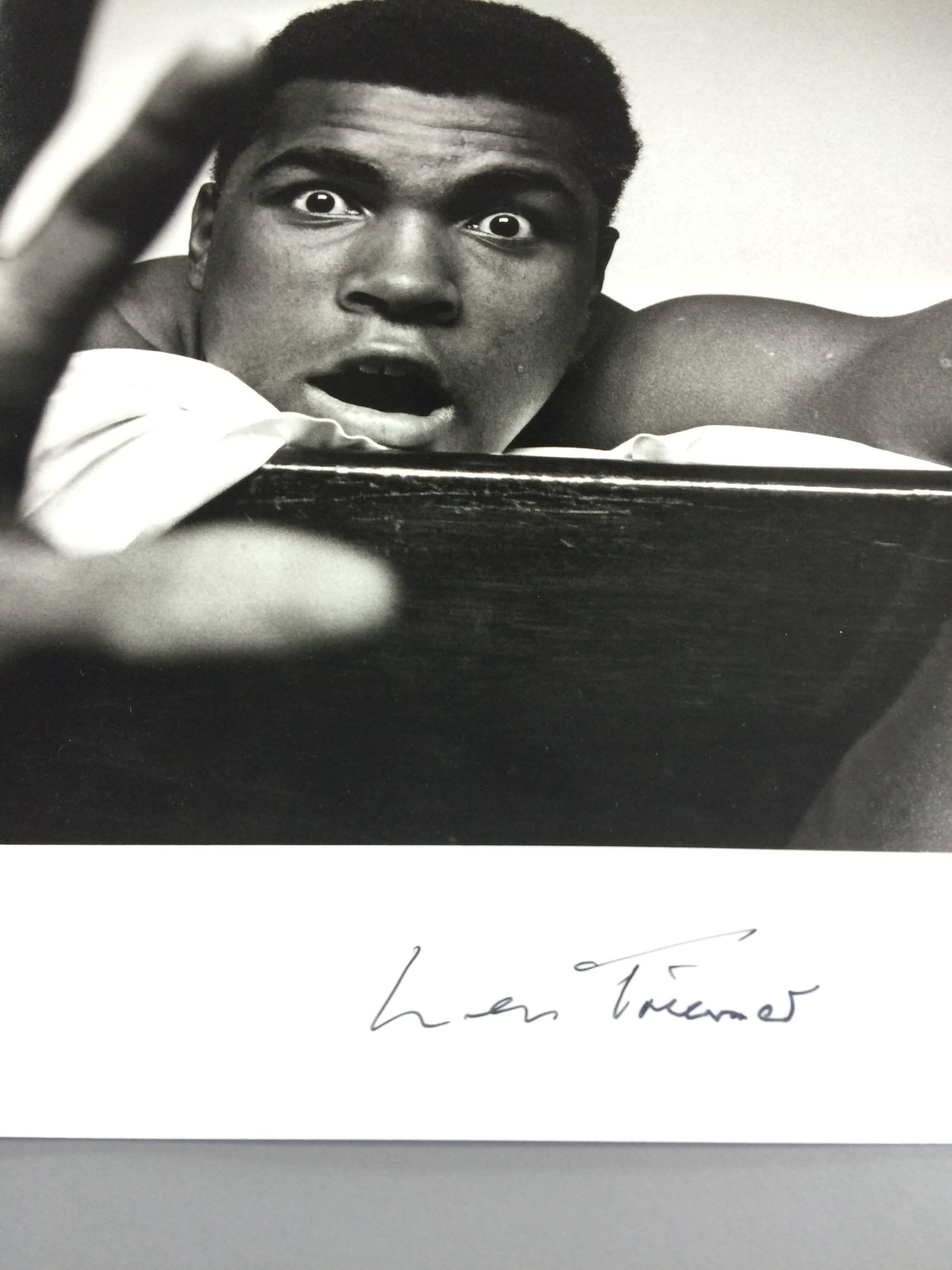 Black and white photograph of American Heavyweight boxer Cassius Clay (later Muhammad Ali) lying on his hotel bed in London in May 1963. He holds up five fingers in a prediction of how many rounds it will take him to knock out British boxer Henry