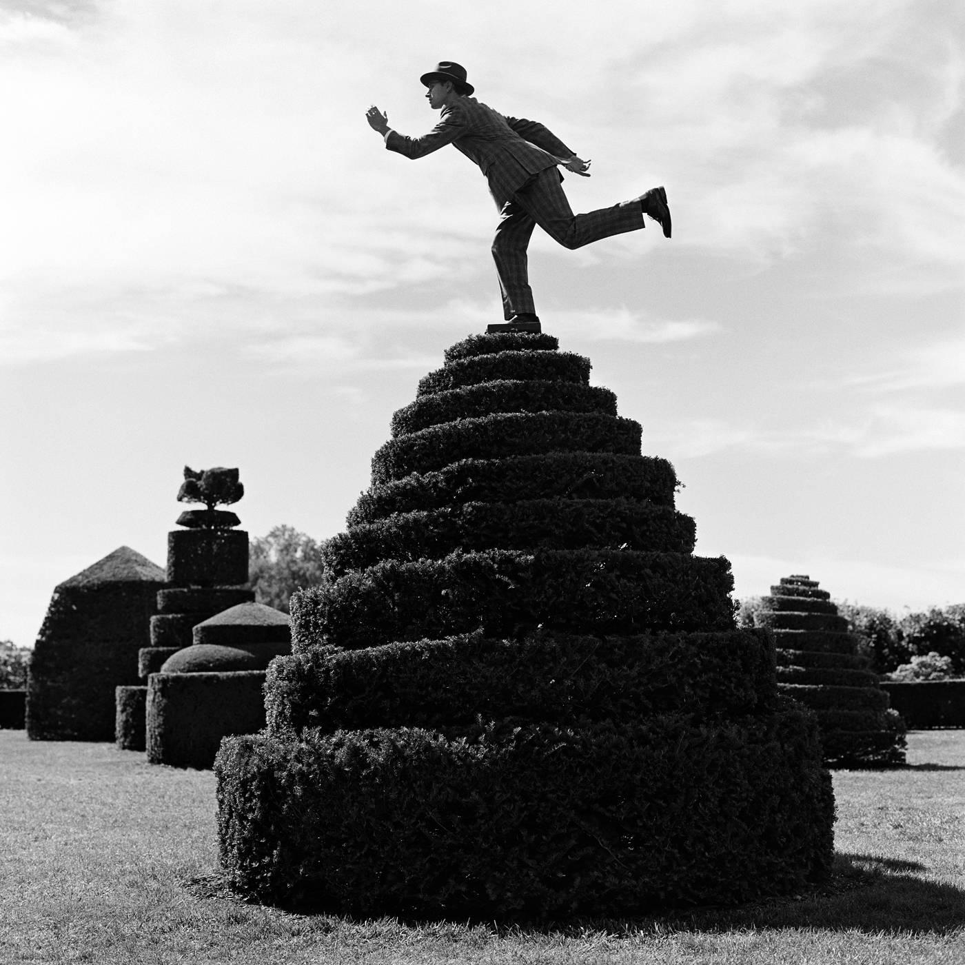 Rodney Smith Figurative Photograph - Reed Balancing on top of Topiary, Longwood Gardens, PA