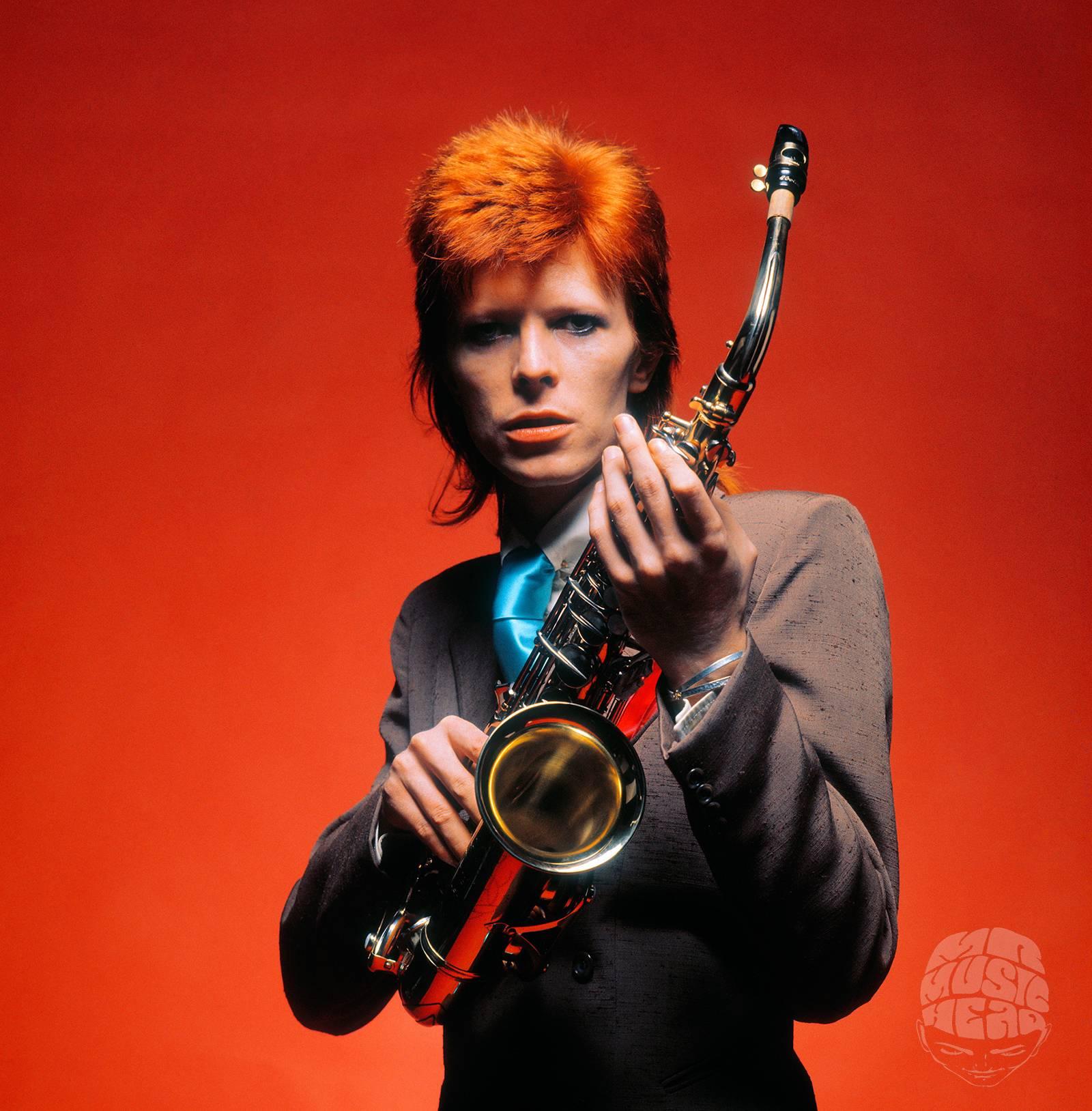 David Bowie posing with a saxophone, shot by Mick Rock in 1973. Bowie began playing the saxophone as a child went on to play the instrument on a number of his songs.

16 x 20 inches
Edition of 90

Mick Rock is often referred to as “The Man Who Shot