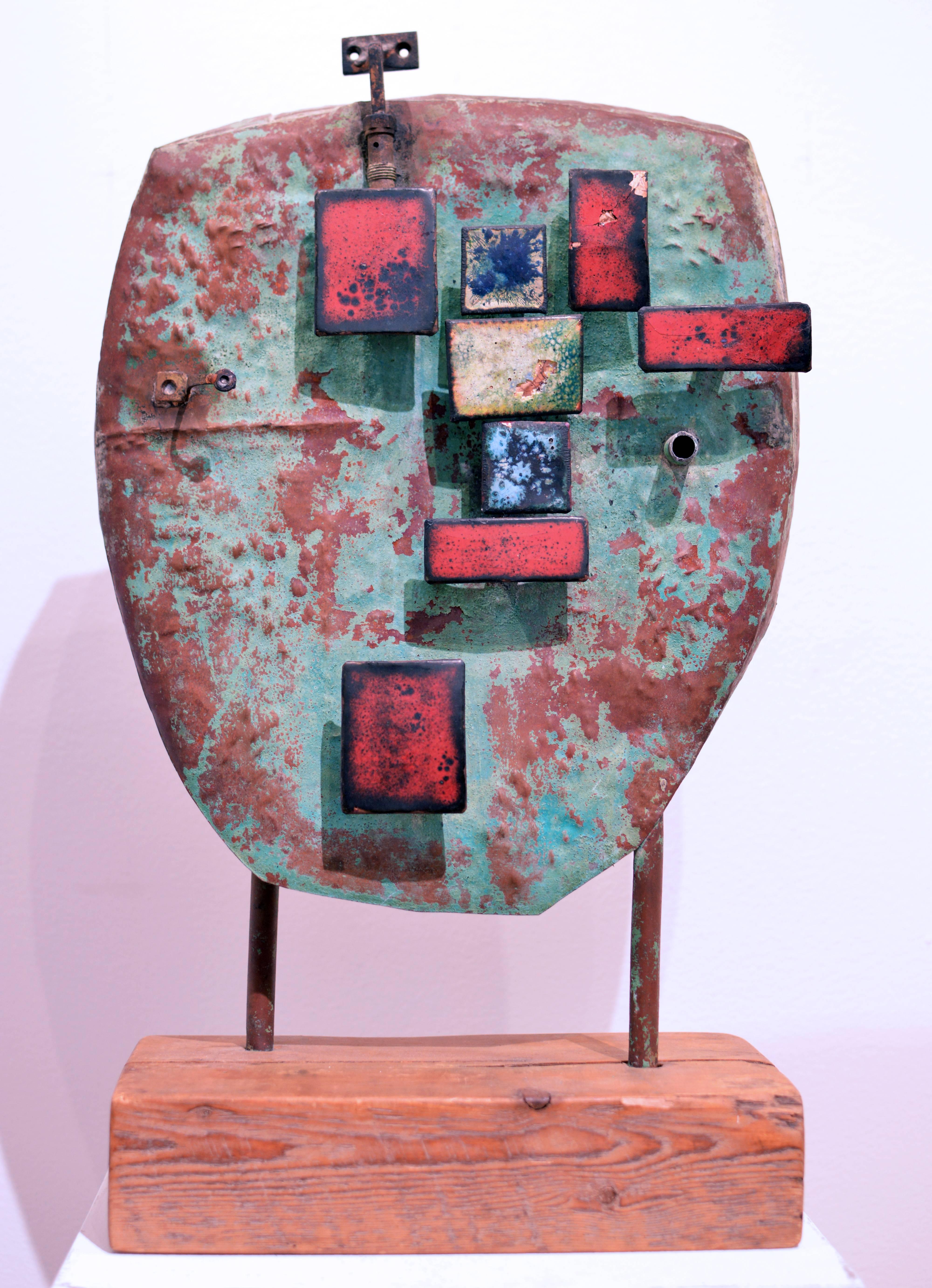"The General" is an abstract sculpture by Modernist artist, Stanley Bate. Made circa 1960, the sculpture is made of wood and metal, and features red, blue, and off-white rectangular shapes over top a textured piece of metal that is reddish and green