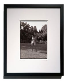 « Un homme dans un champ » - Photographie en noir et blanc d'un homme nu seul dans un champ, encadrée