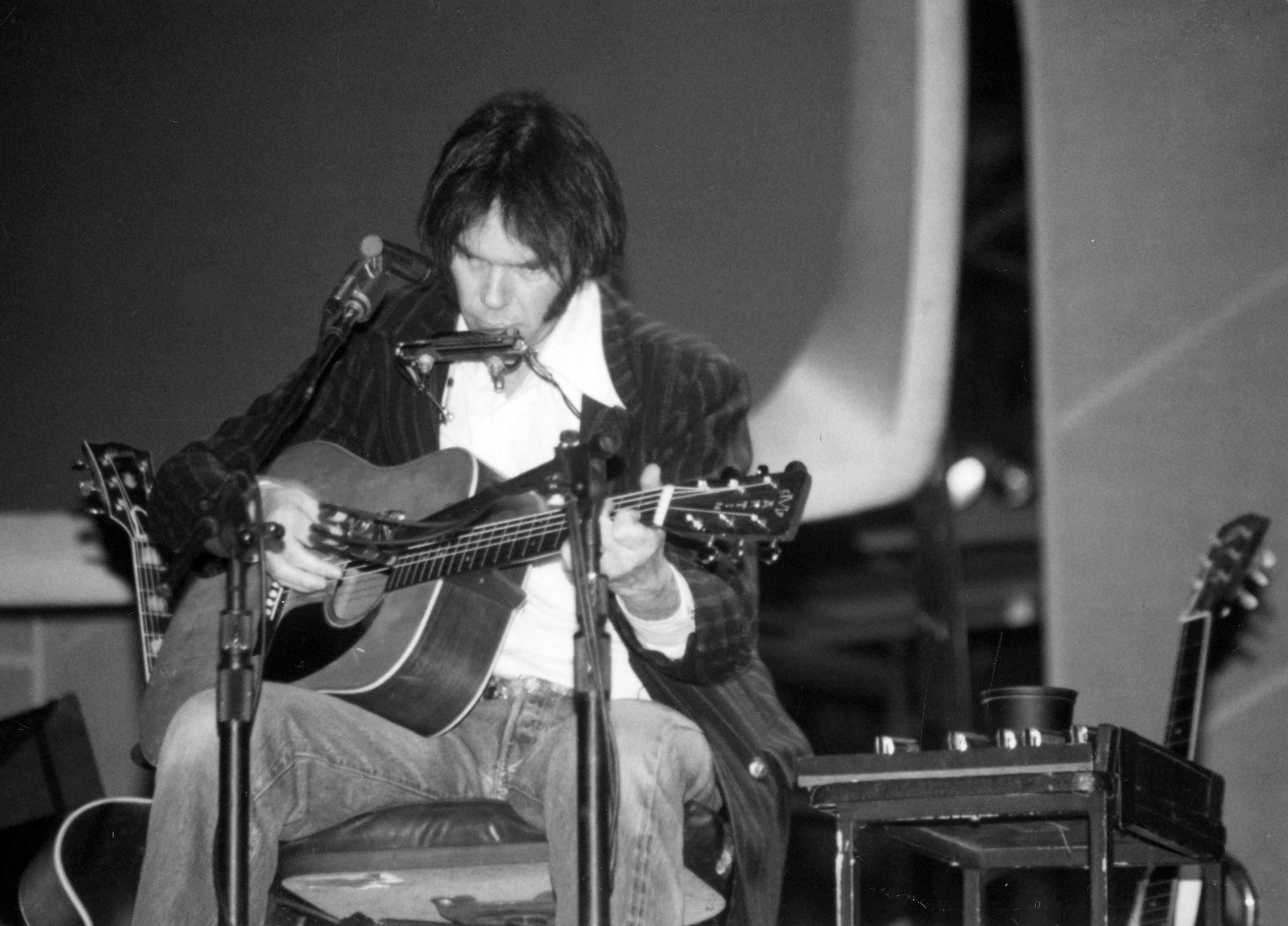 David Plastik Portrait Photograph - Neil Young Playing Guitar and Harmonica on Stage Fine Art Print