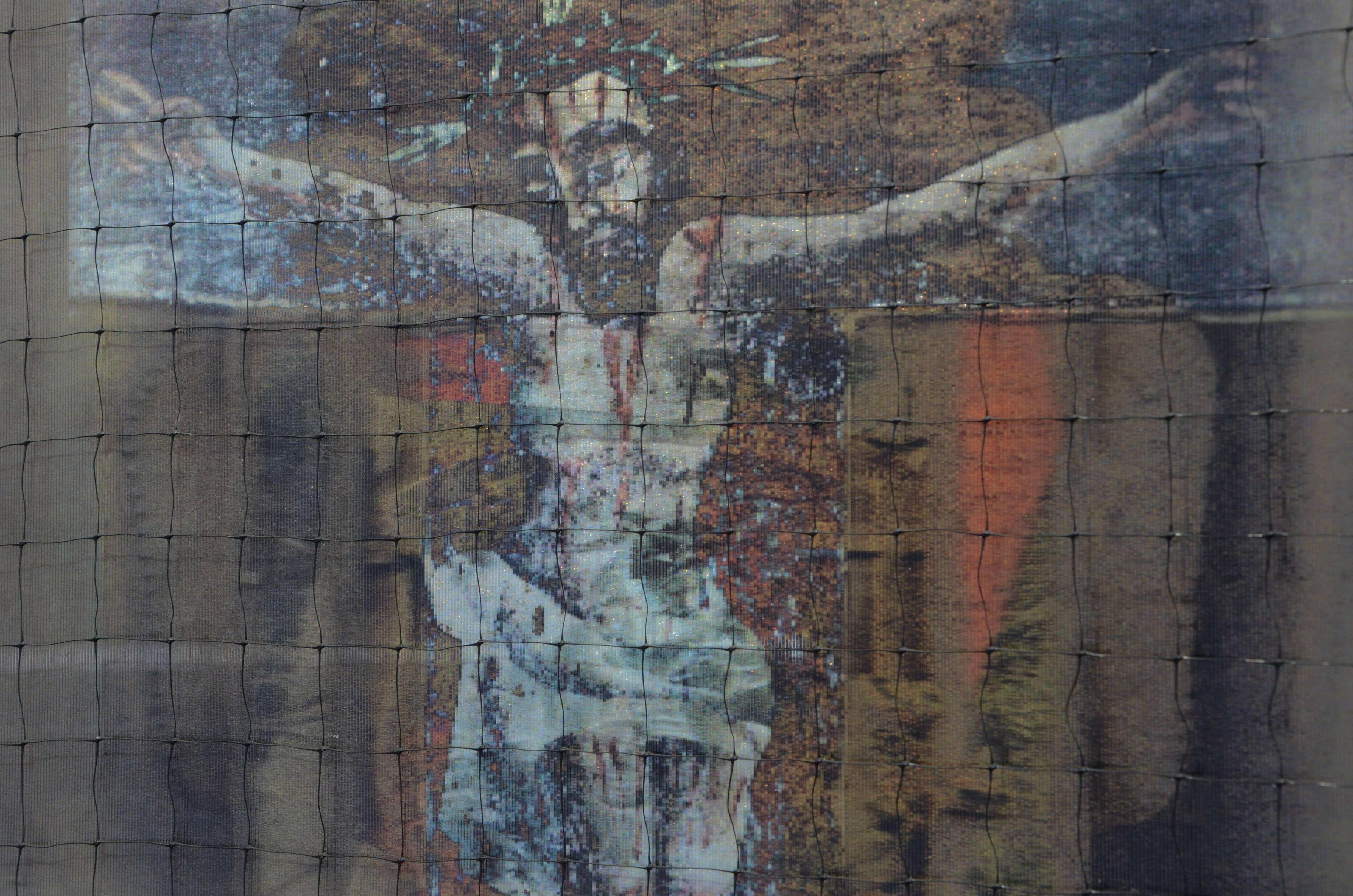 Dorothy Simpson Krause’ “Bleeding Jesus” is a 12 x 12 inch lenticular work with mixed media. The lenticular image of Jesus with the crown of thorns floats over a shimmering background, a golden halo and a silver cross.  The work has the feel of a