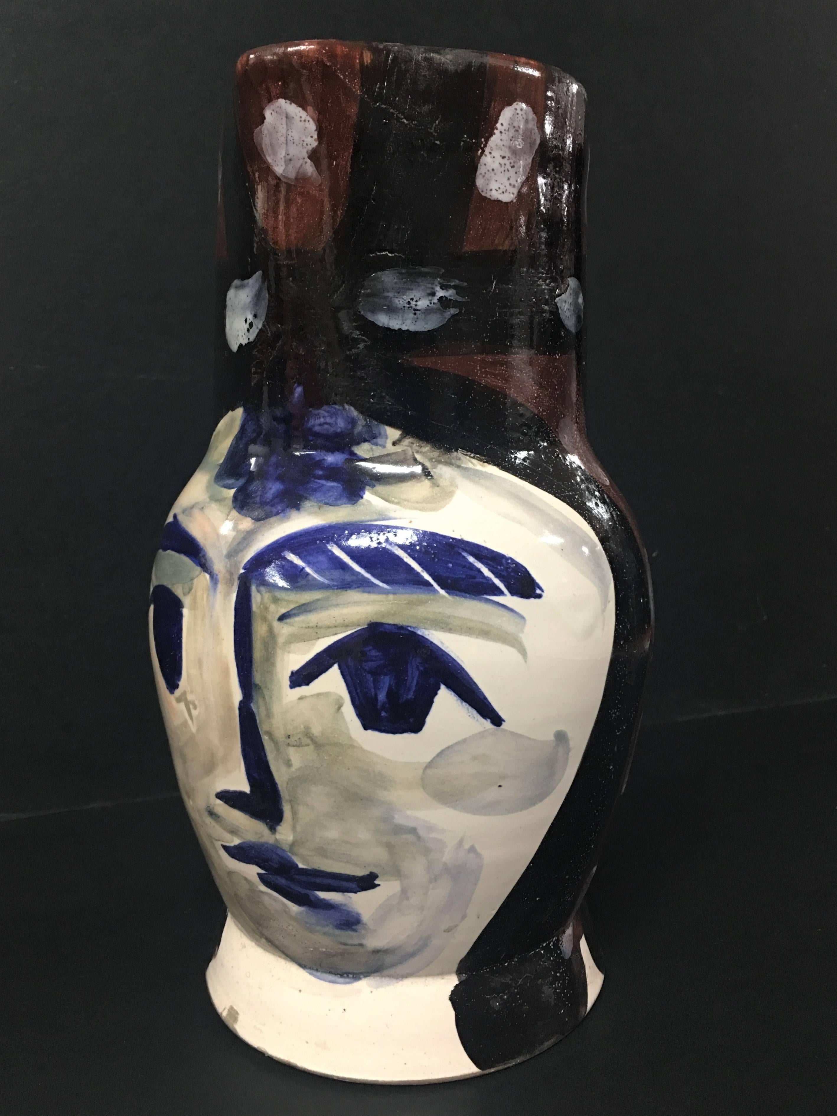 Esta pieza es una jarra torneada A.R. creada por Pablo Picasso en 1953. Está hecha con arcilla de barro blanco, decoración en engobes y óxidos bajo vidriado parcial cepillado con manchas de esmalte blanco en azul, rojo, blanco, marrón y negro. Lleva