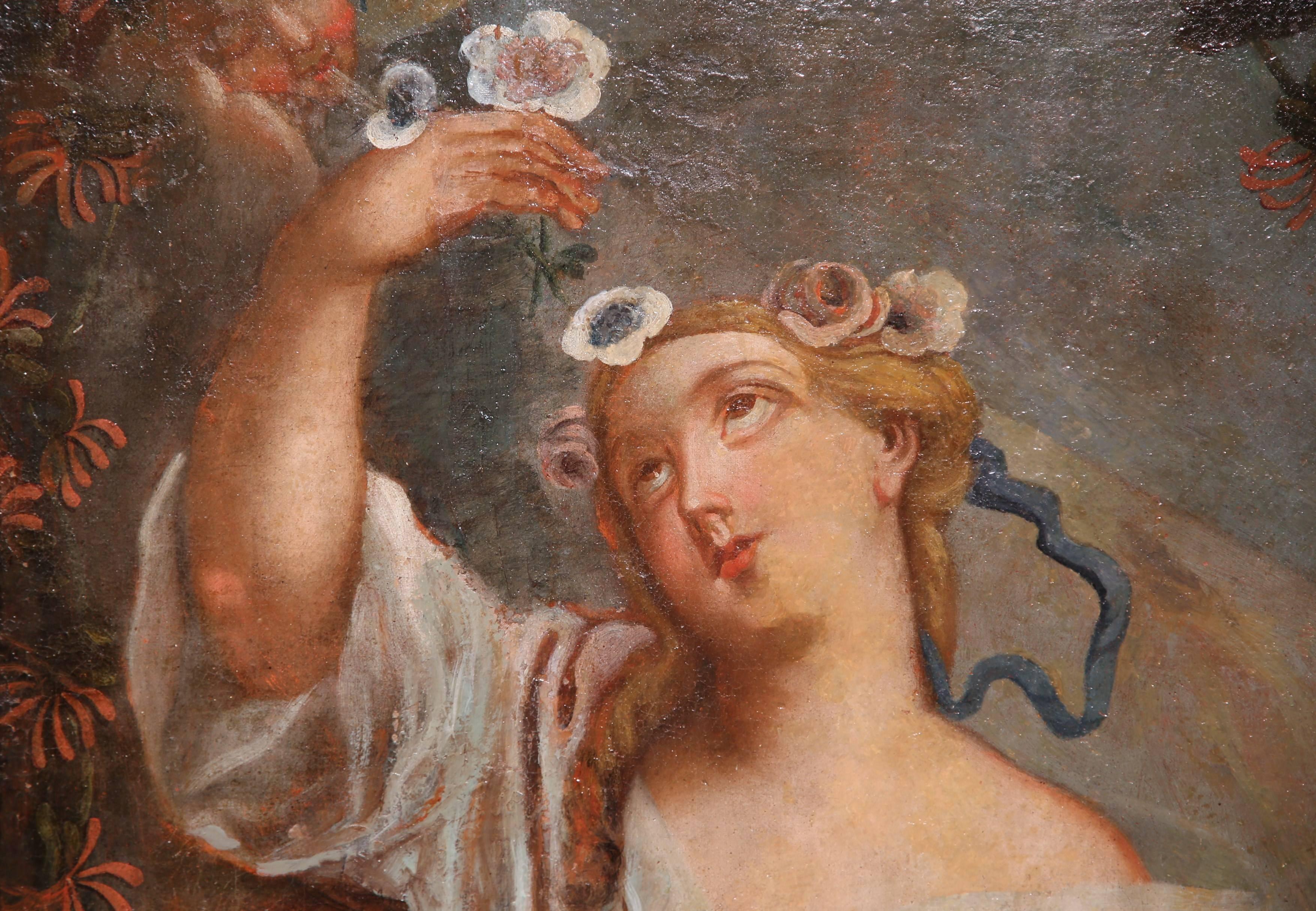 This beautiful, antique oil on canvas was painted in France circa 1720. The portrait depicts a young beauty holding flowers while a cherub watches from the sky. The painting has a beautiful rococo style, a soft pastel palette, and graceful facial