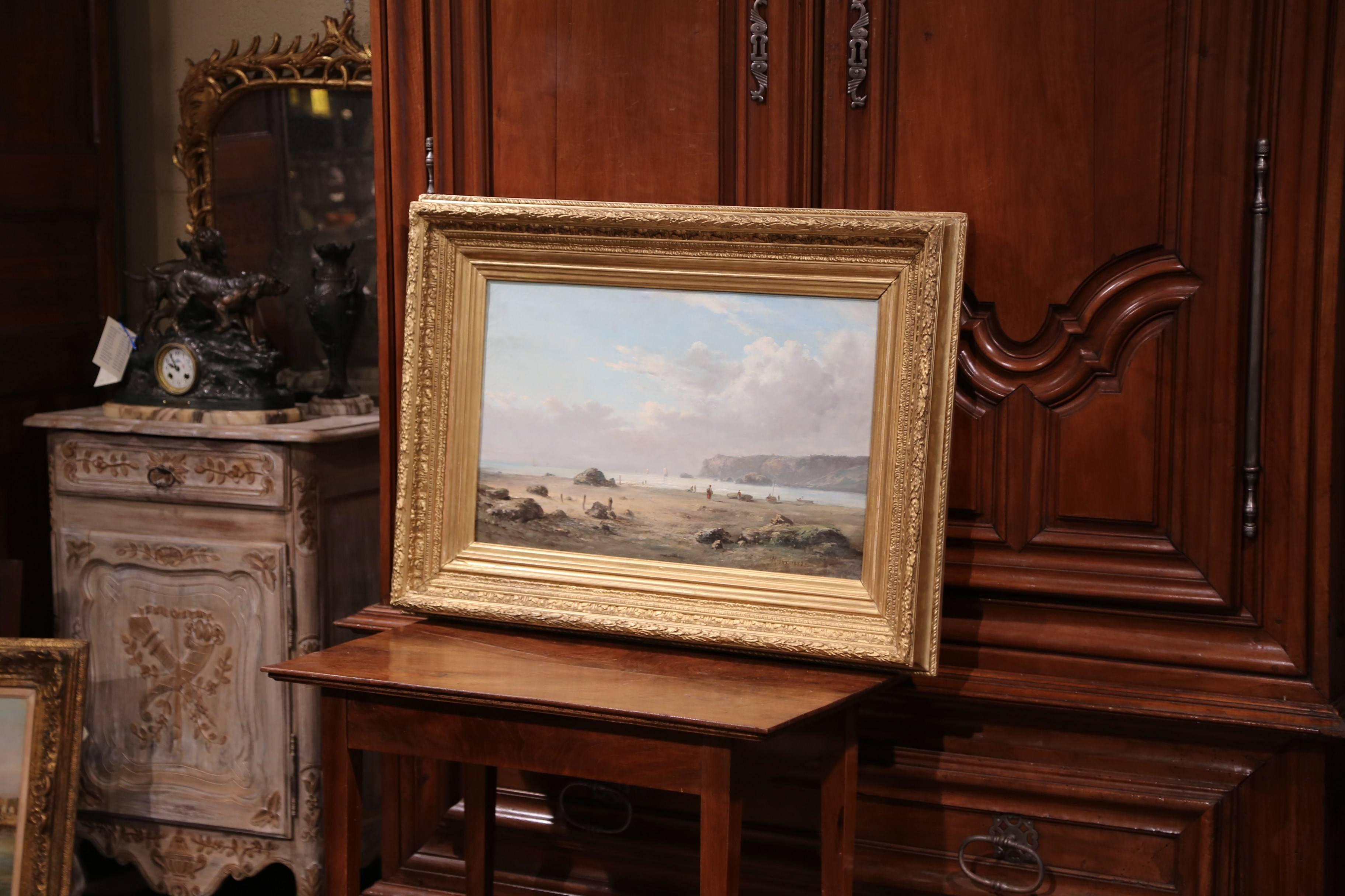 This beautiful oil on canvas painting set inside the original carved gilt wood frame, was created in France at the end of the 19th century; the landscape composition features a shoreline in Brittany with a picturesque beach in the background. The