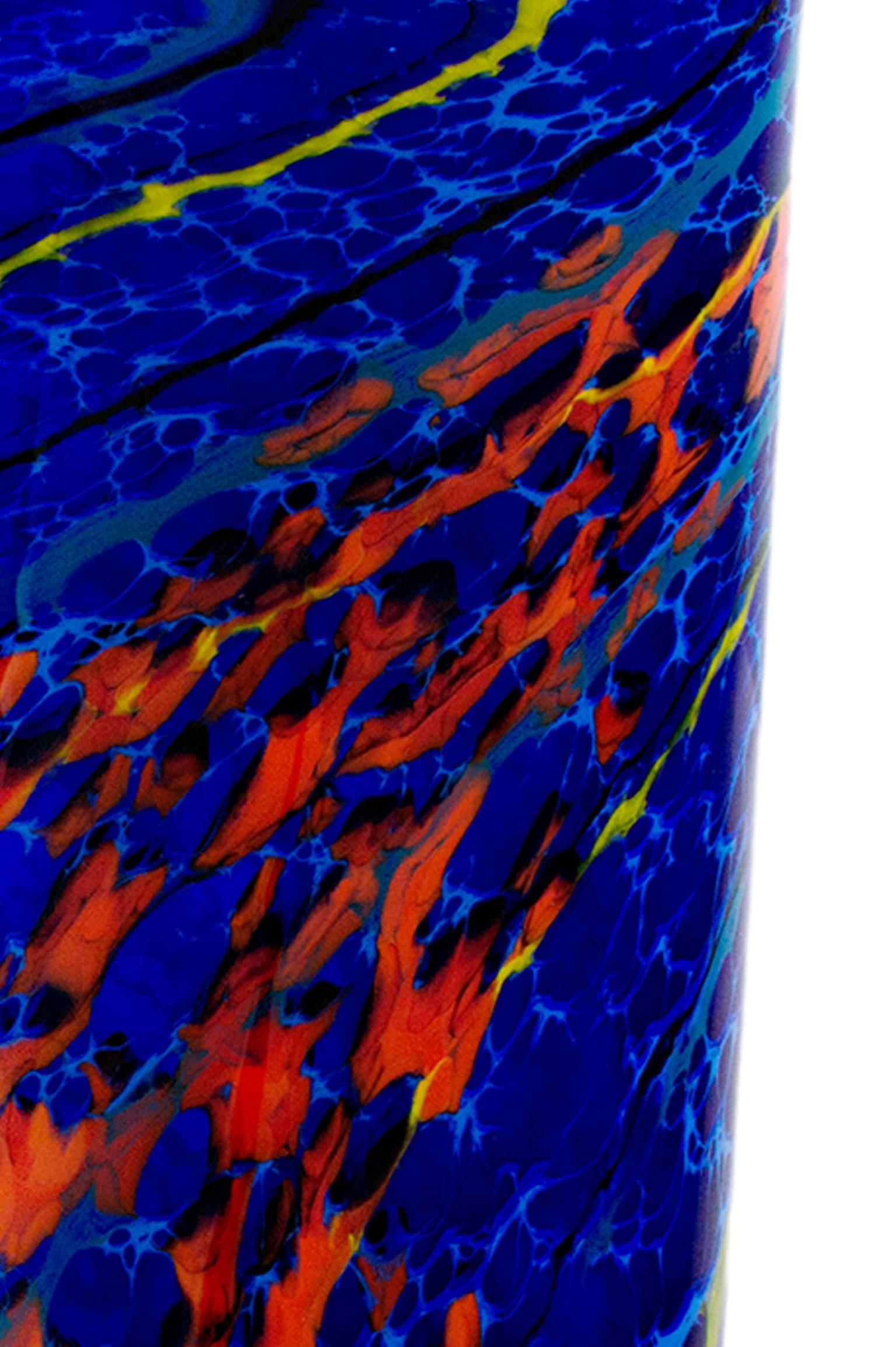 This piece is a hand blown glass vase by Ioan Nemtoi. The vase is a deep blue blue and has flecks of bright red and lines of yellow, black, and gray throughout. 

16