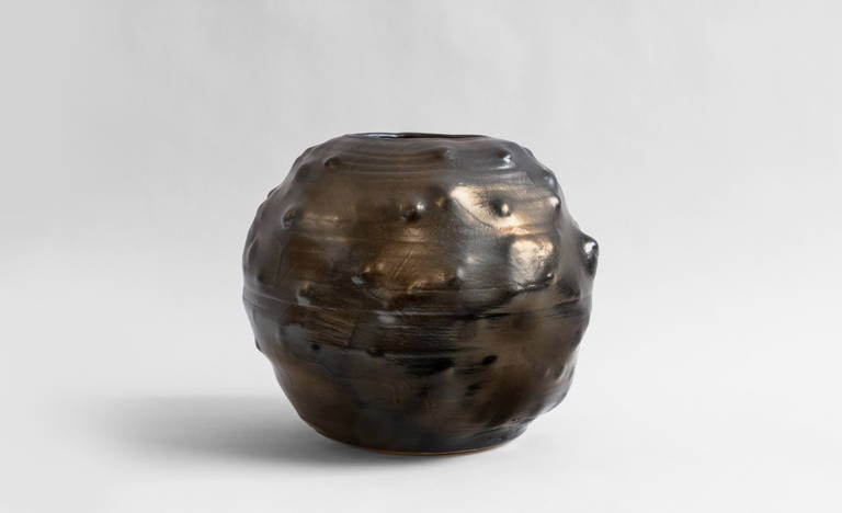 Stoneware ceramic vessel with metallic glazing.
