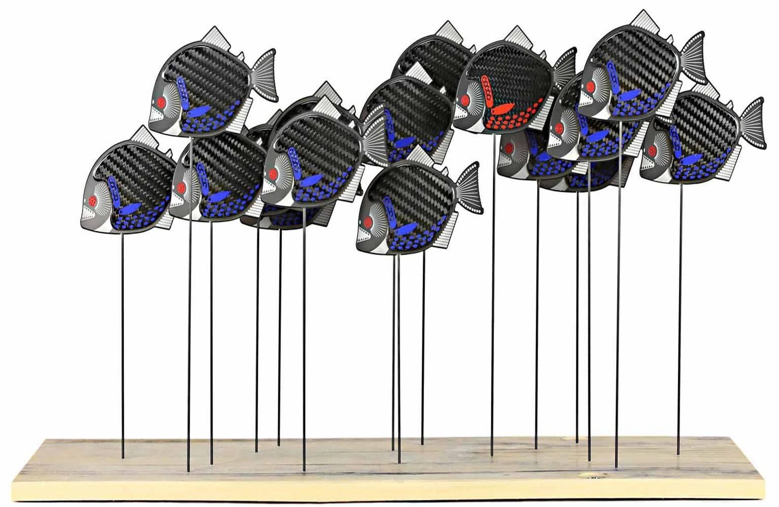 Amazon School by artist Alastair Gibson. This sculpture shows a school of stylised racing piranha fish mounted on a used FIA legality perma-glass underfloor plank. The sculpture is limited to 25 pieces and signed and editioned by the artist on