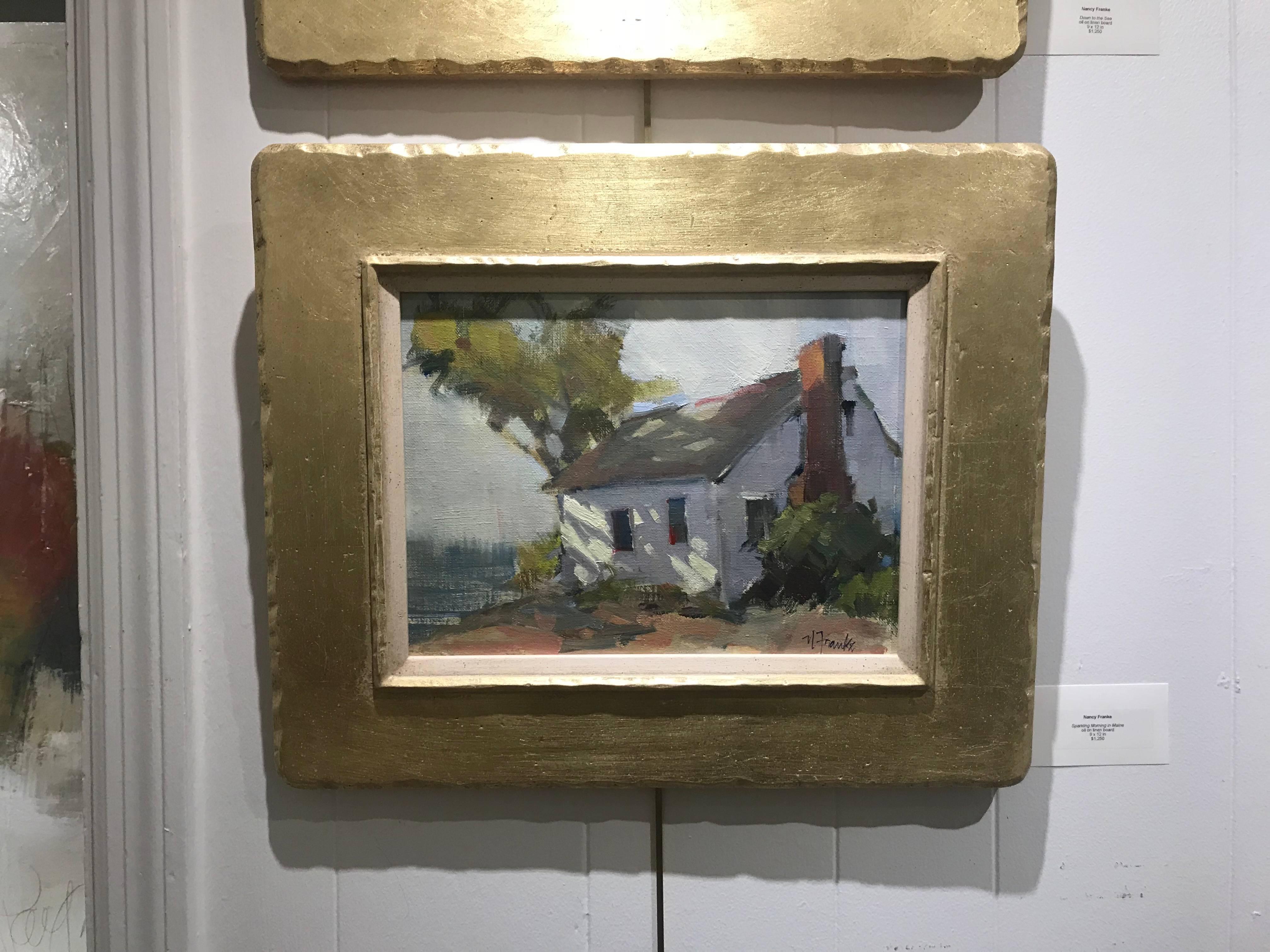 'Down to the Sea' is a framed oil on linen board painting created by American artist Nancy Franke in 2017. Set inside a handmade frame finished with 14k gold, the painting depicts a simple house with slanted roof marked with a large chimney on its