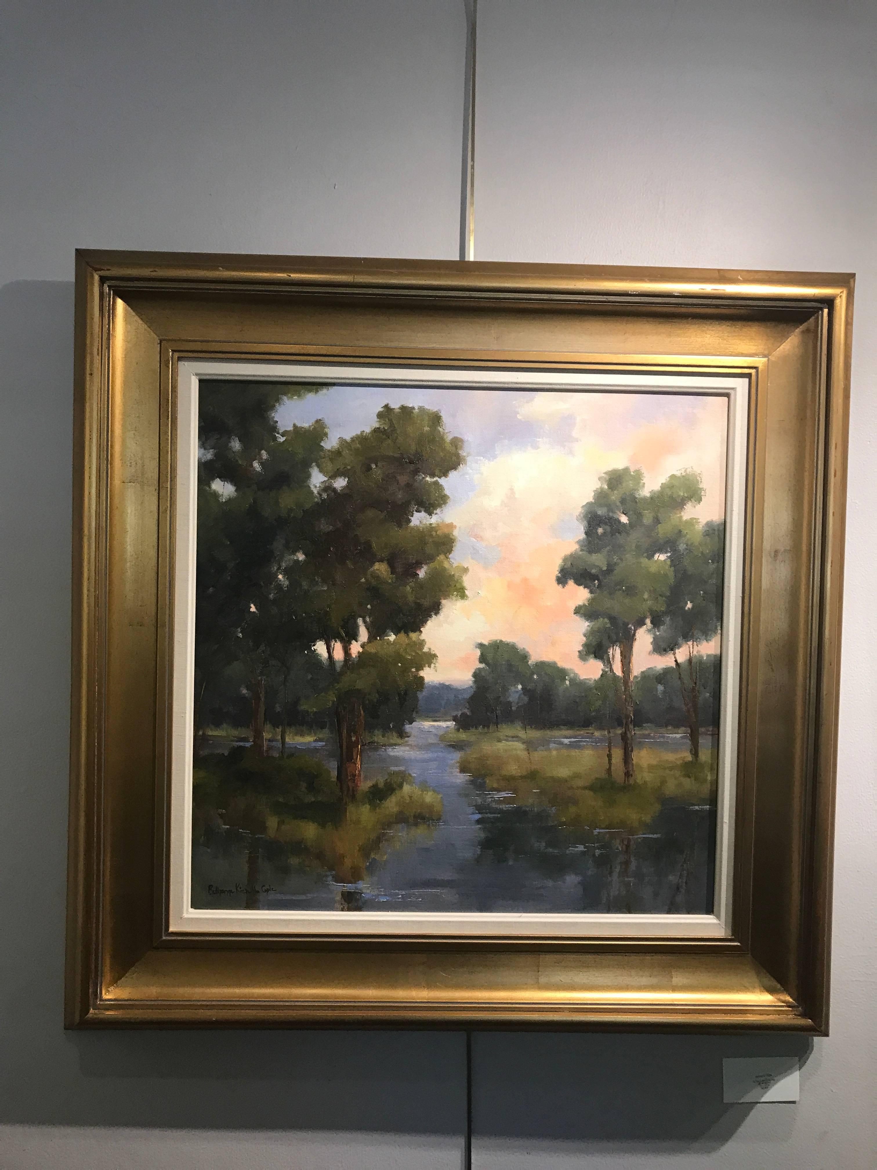 This medium size landscape painting from Virginia plein air artist Bethanne Cople is titled A Tidewater Evening. Made in 2010, it is the perfect southern landscape showing sunset on a beautiful lake. The pretty pinks in the sky mark the end of a
