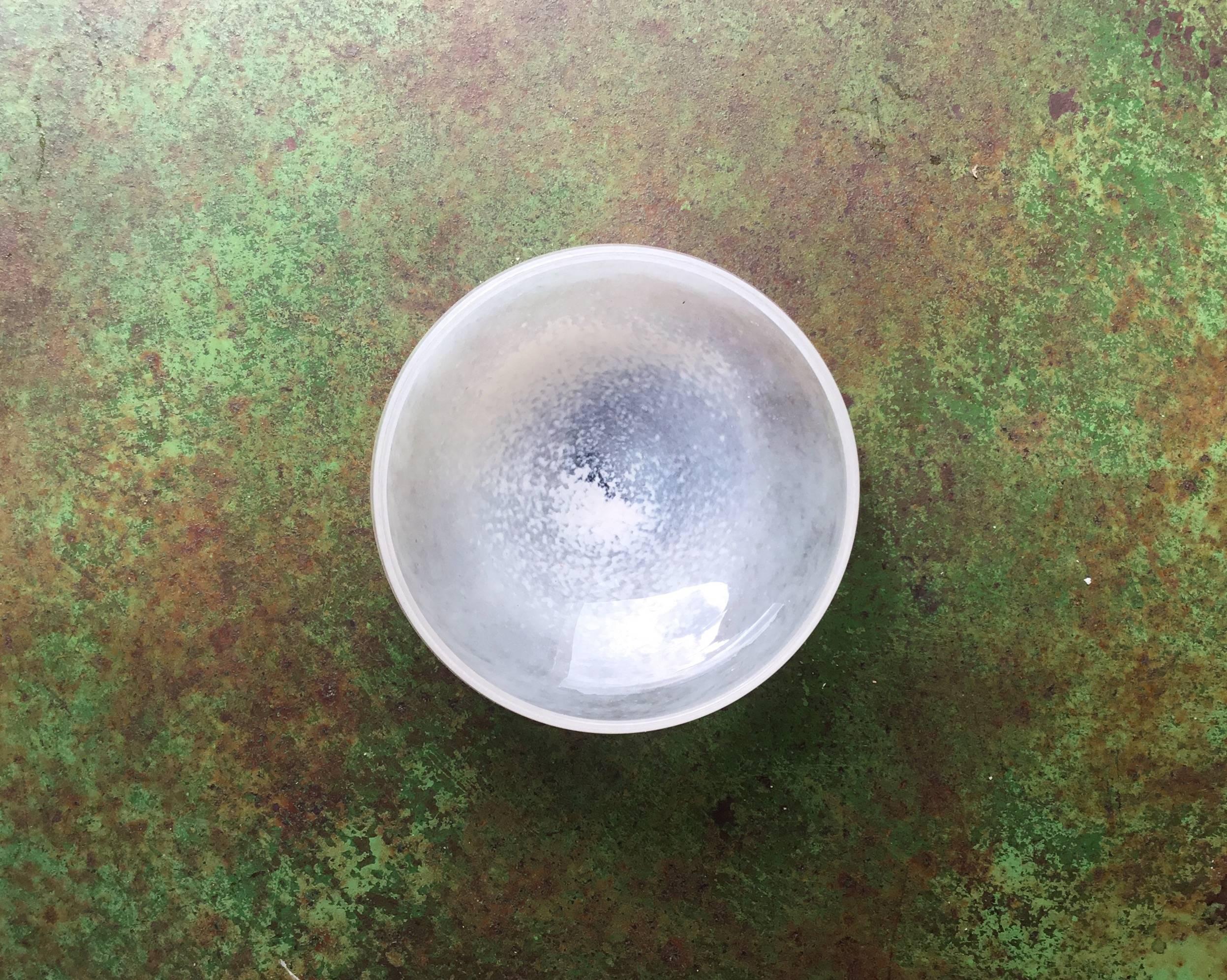 A contemporary glass bowl from a specialist glass workshop in Osaka.

The iridescent pearl-like quality of this bowl has a spiralling cloud like effect. It makes for for an extremely graceful object that can be displayed either on its own or layered