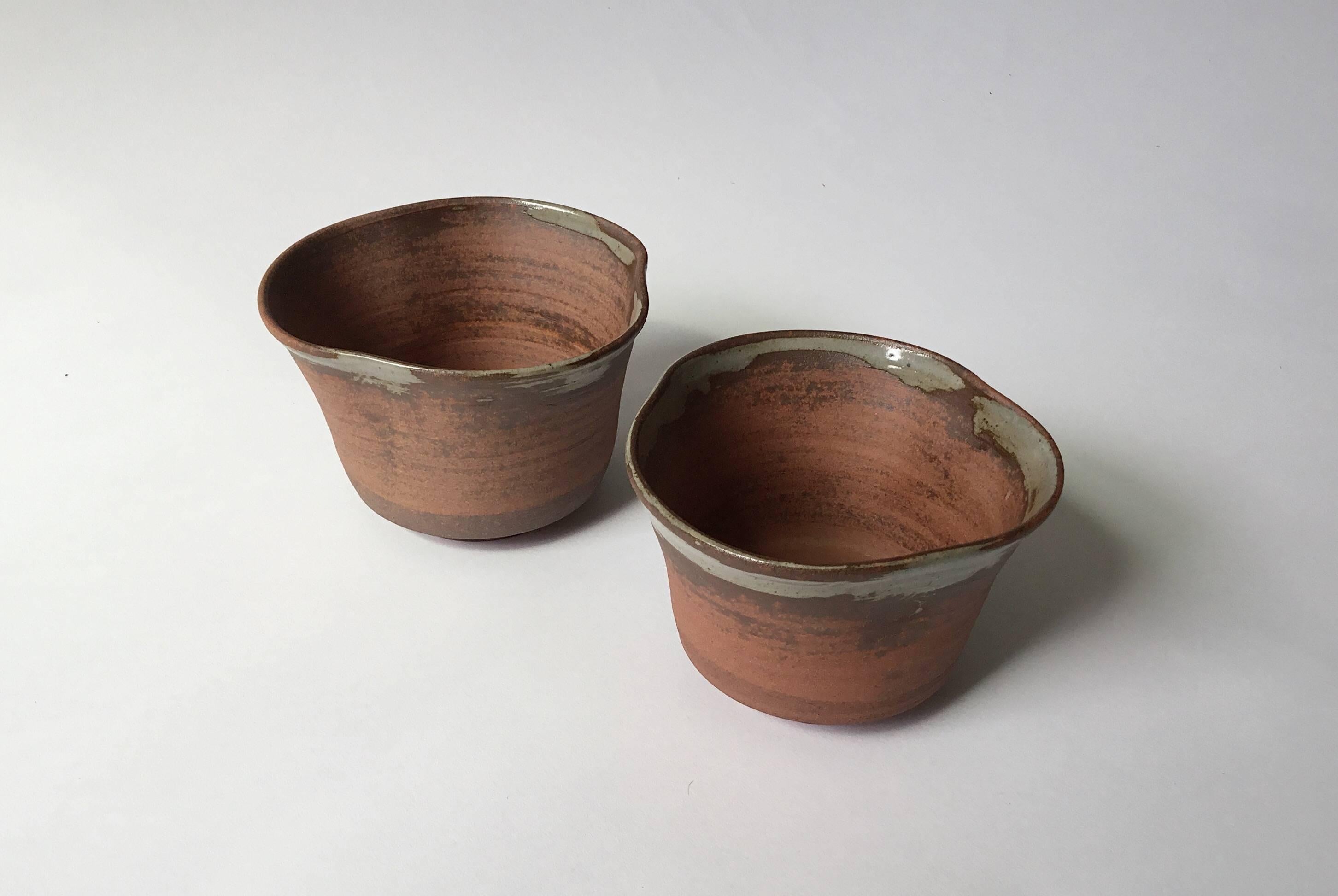 This pair of Japanese ceramic bowls were sourced from a small pottery workshop in the Nishiki market in downtown Kyoto.

Despite their uniform turned base the raw reddish clay forms have each been hand-pulled into a uniquely balance shape at the lip