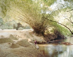 Junger Junge, der Sand aus der Flussbank sammelt