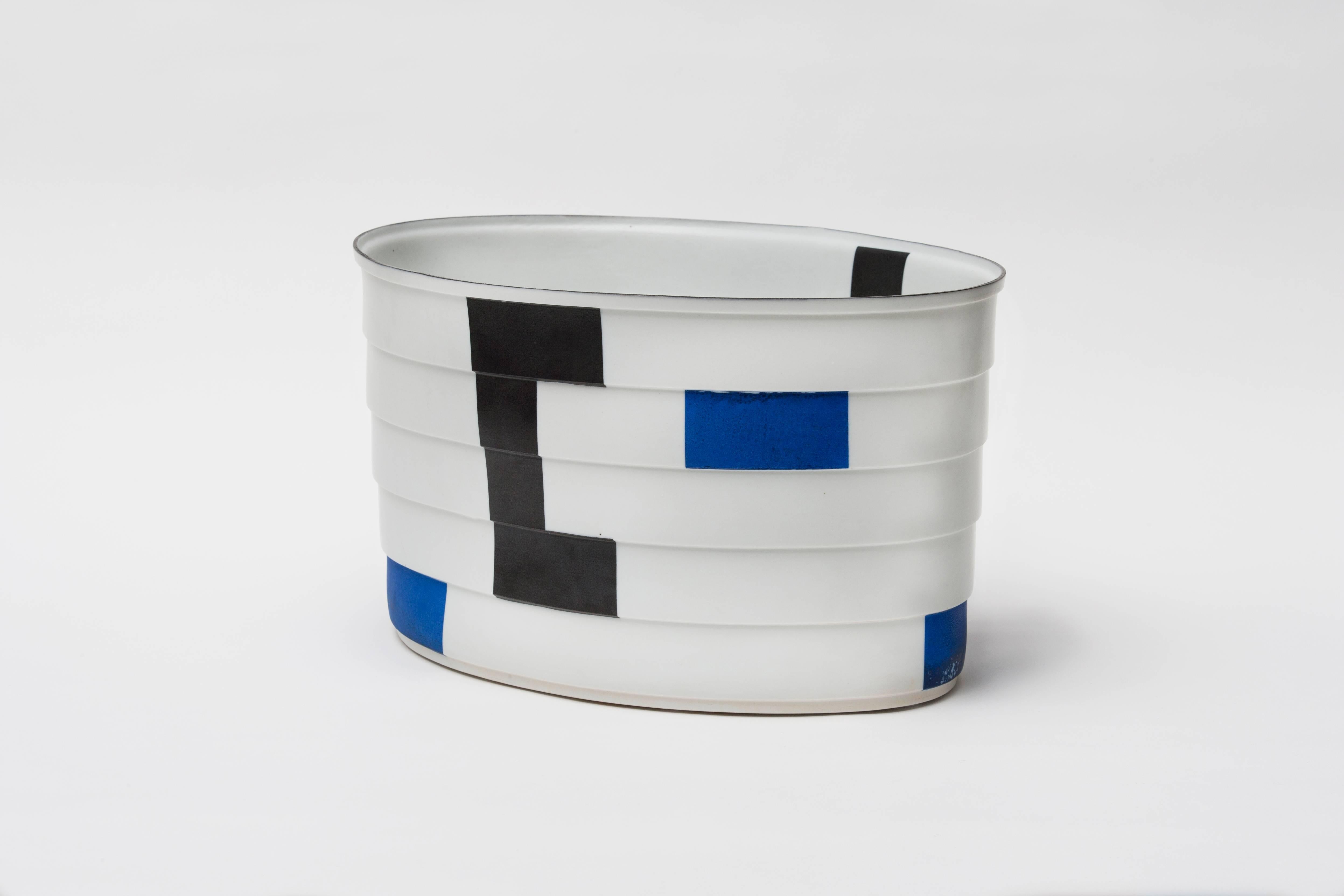 Bodil Manz is a ceramicist known for her use of ultra-thin, translucent eggshell porcelain to create distinctive cylindrical forms, anchored by bold, geometric abstractions in a style evocative of Russian Suprematism. Manz was born in Copenhagen in