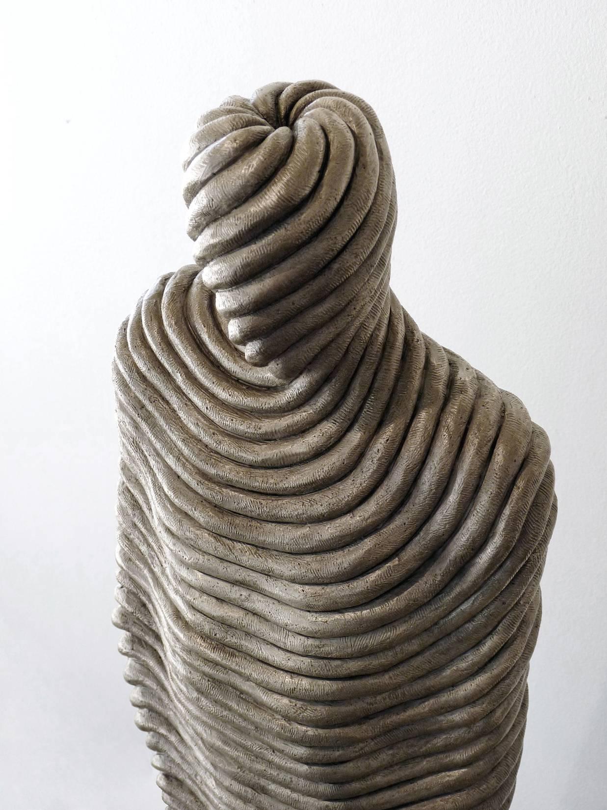 Cette sculpture figurative en bronze d'Emil Alzamora représente une figure masculine apparemment enveloppée de la tête aux pieds dans un matériau texturé ressemblant à une corde. 