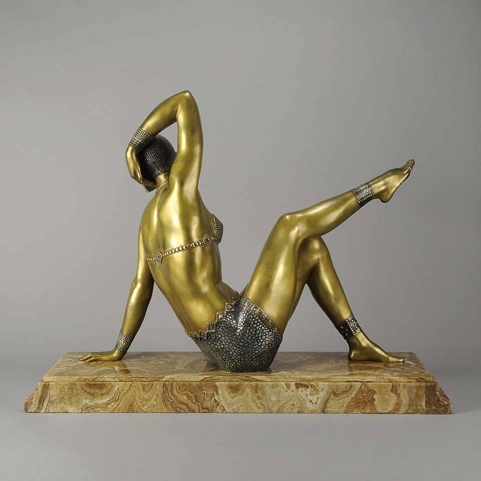 Magnificent and imposing exotic cold painted gilt bronze figure of a beautiful beach girl seated in a seductive pose wearing a two piece swimsuit with a headdress and ankle bracelet, exhibiting excellent colour and very fine hand finished detail,