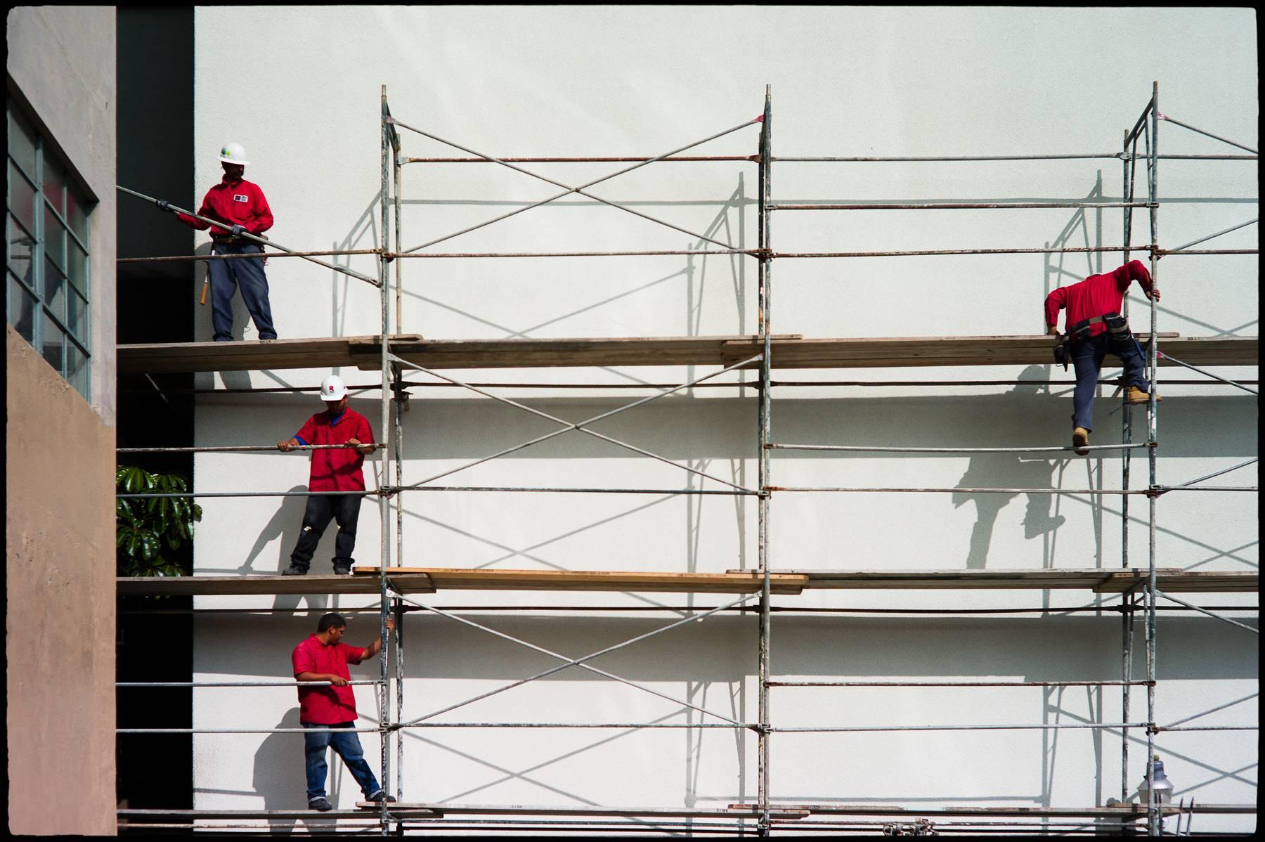 Mark Berndt Color Photograph - A Scaffold of Men in Red