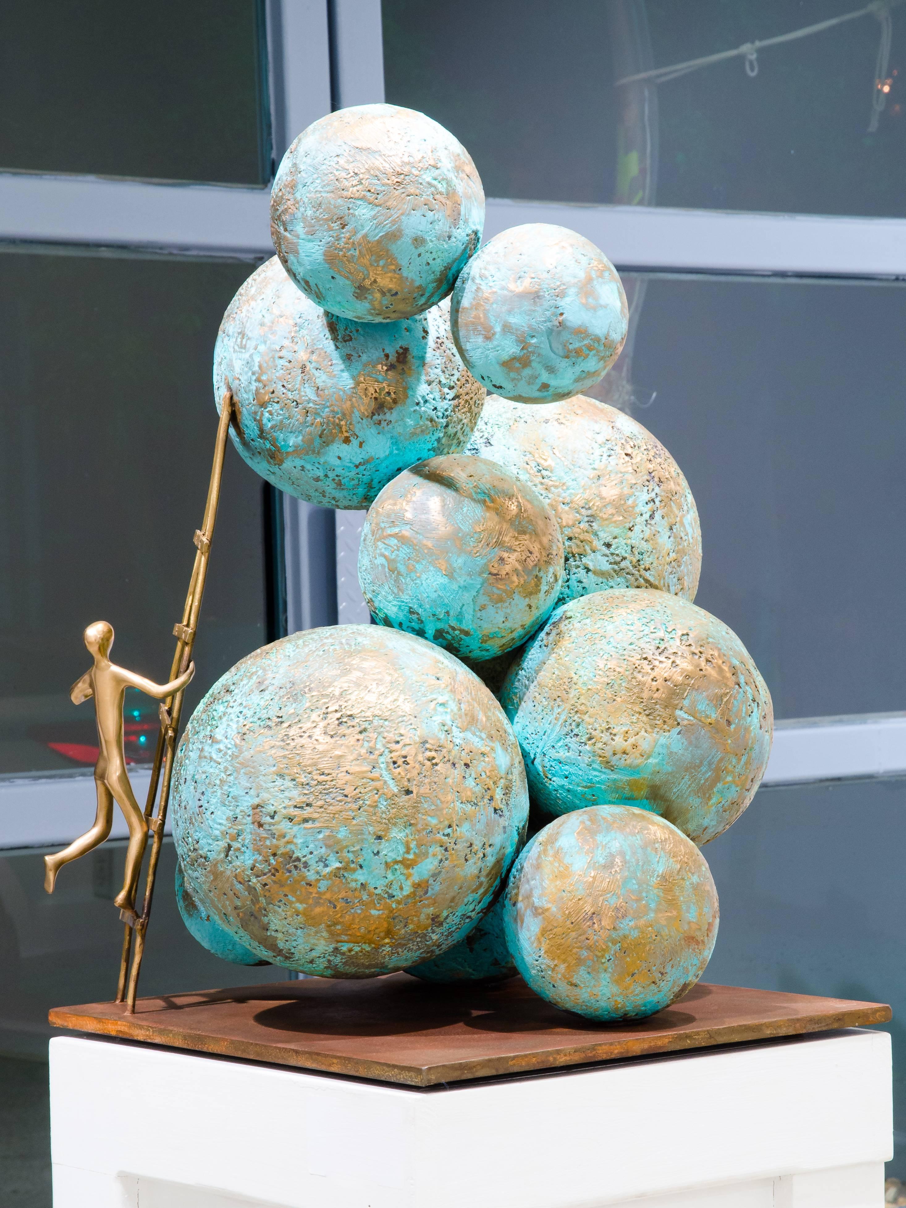 Climbing worlds is a contemporary bronze sculpture where Beatriz Gerenstein shows spheres with blue, green and golden tones floating as were planets in the outer space. 
The golden ladder that completes the composition adds an intriguing element.