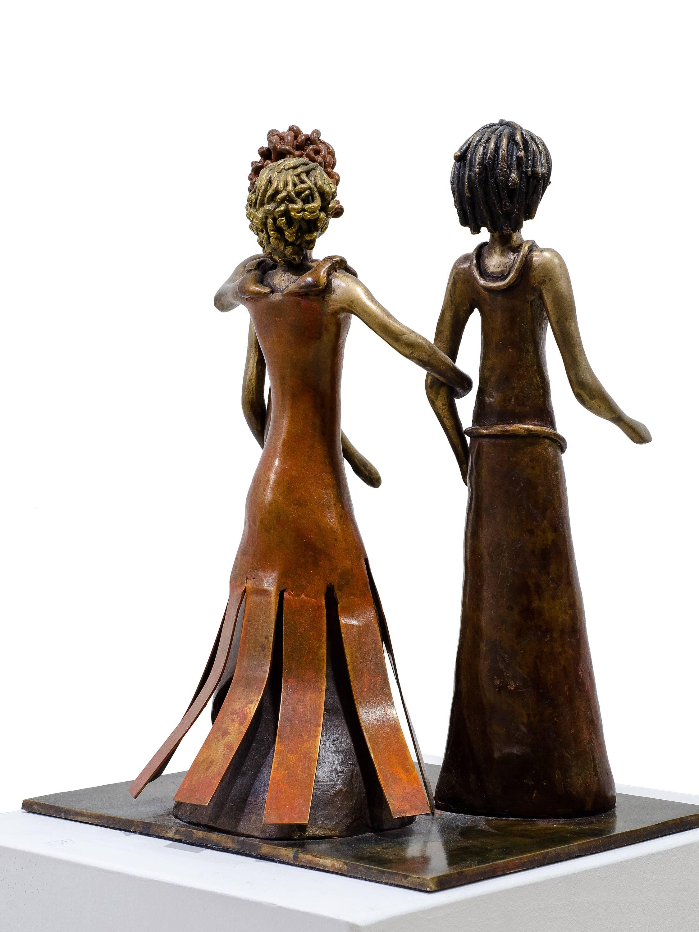 Friendship is a bronze sculpture by Beatriz Gerenstein that shows three female figures walking together apparently to the same place or in the same direction. The woman in the middle has her arms on the shoulders of the other two. They wear elegant