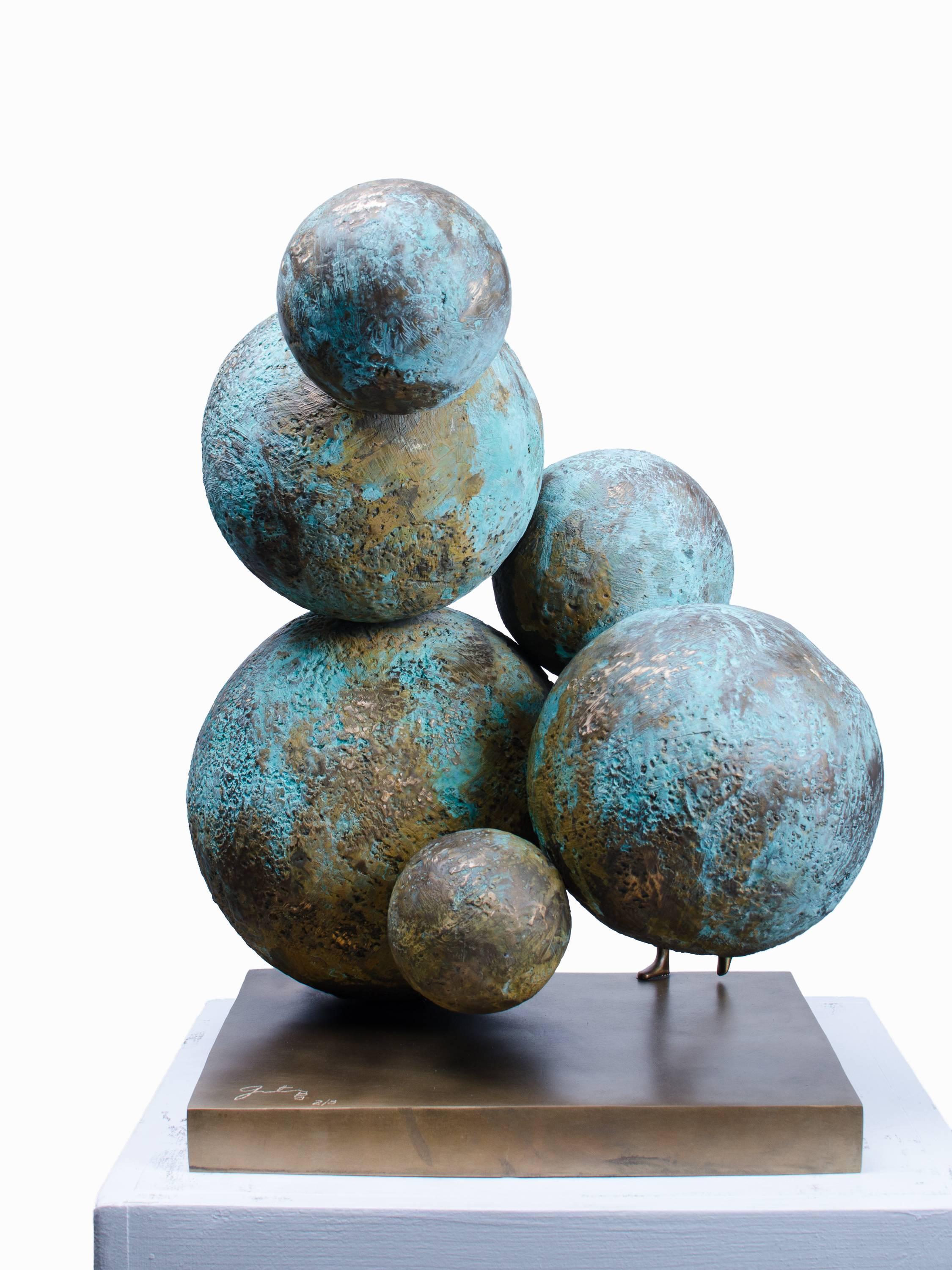 Breaking New Grounds is a contemporary sculpture by Beatriz Gerenstein. It shows a human figurine and some spheres patinated with golden and blue tones like planets are seen from the space.  The figurine is facing, actually walking between the